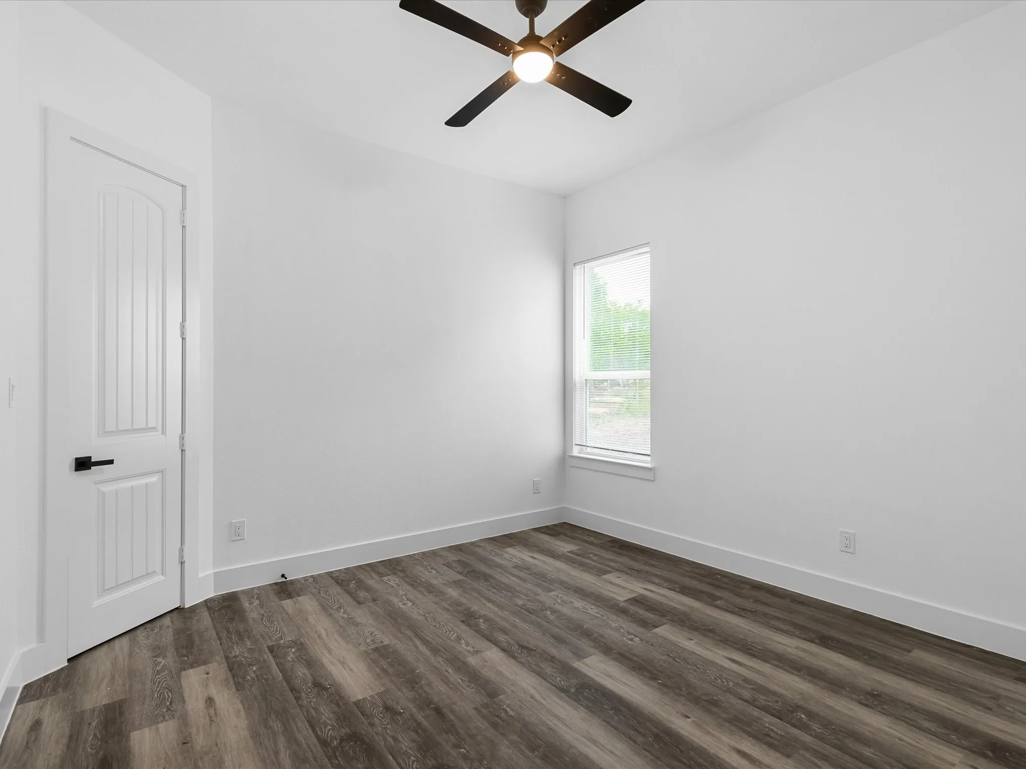 Wood-finish flooring, white walls, and a ceiling fan with integrated lighting