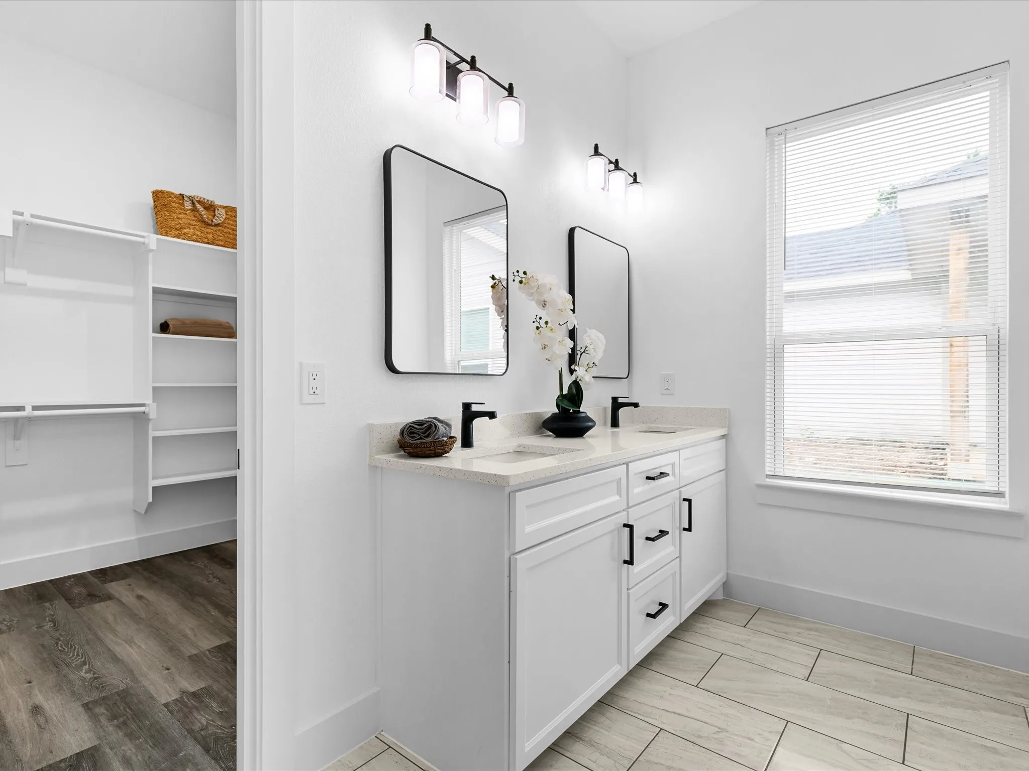 Dual vanity with white cabinetry, light-toned countertops, and matte black fixtures