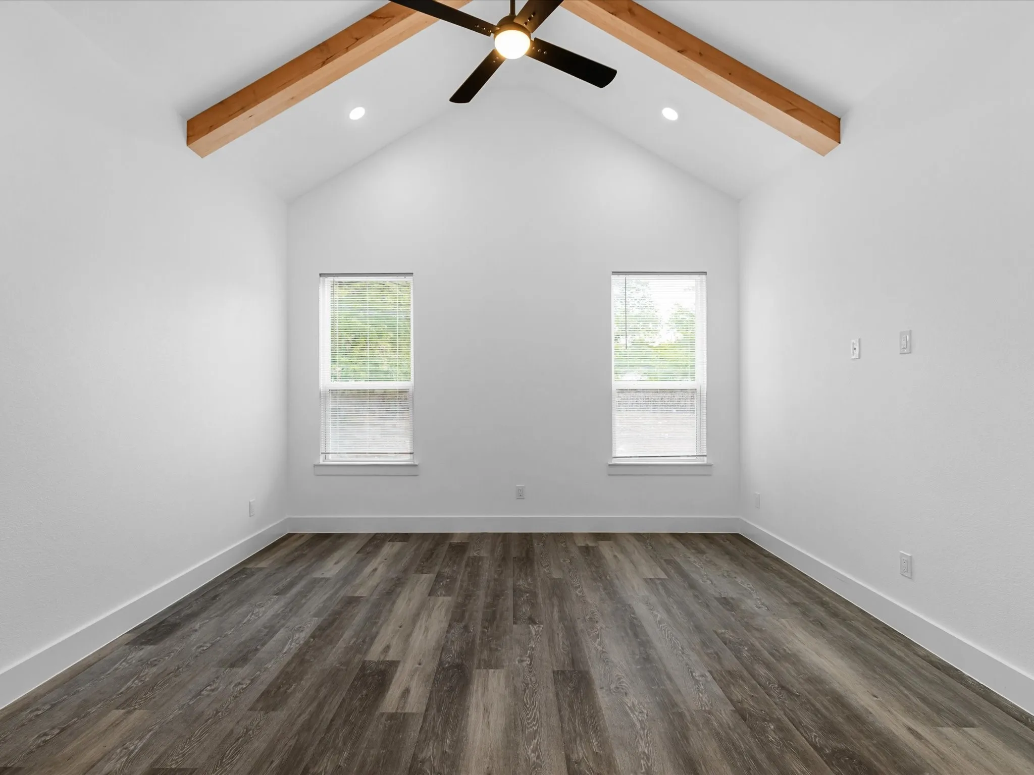 Vaulted ceiling with exposed wood beams, ceiling fan, recessed lighting, and wood-finish flooring