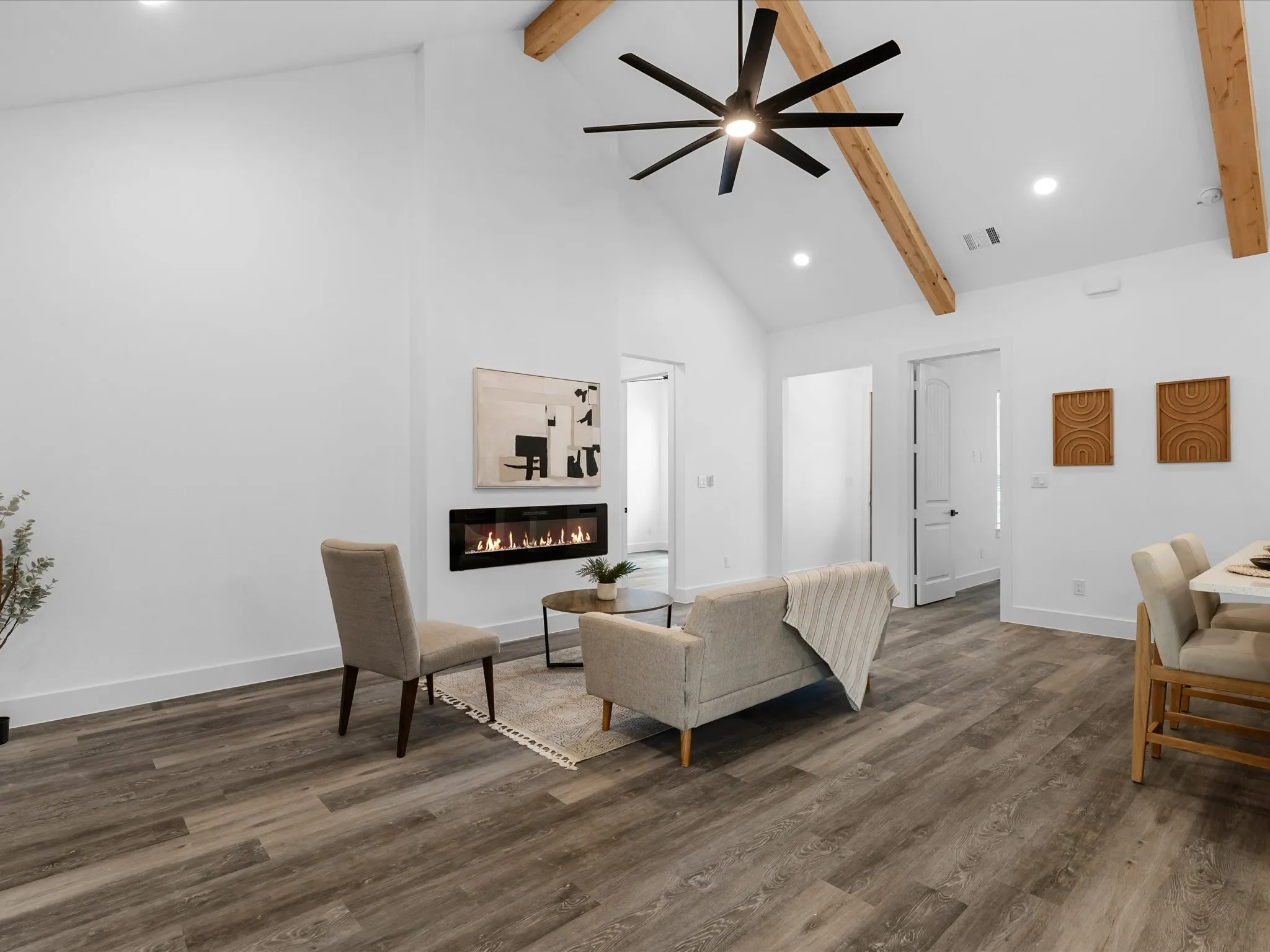 Vaulted ceiling with exposed wood beams, recessed lighting, wood-finish flooring, and a built-in linear electric fireplace
