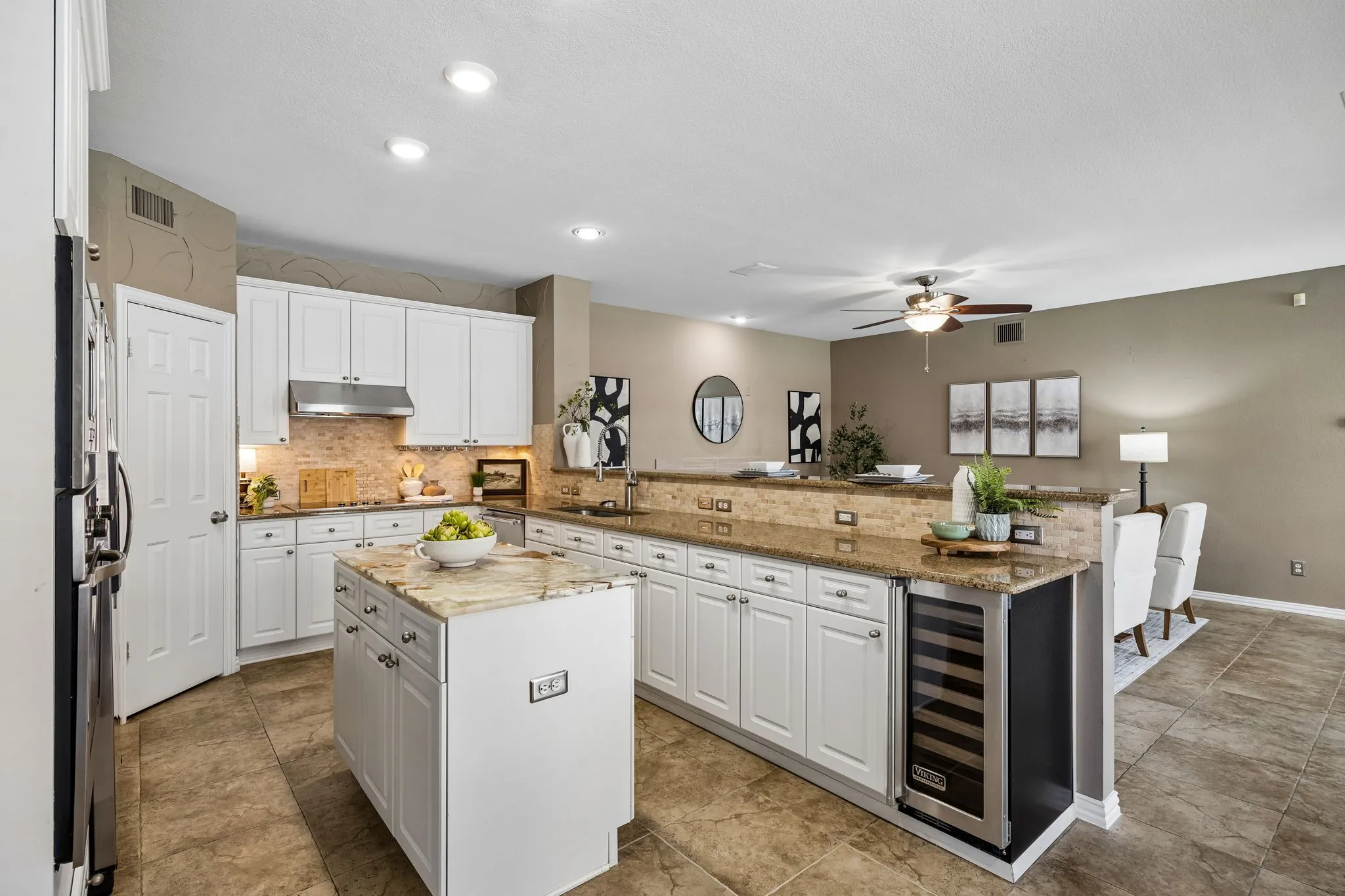 Kitchen featuring white cabinetry, stone countertops, a central island, stainless steel appliances, and tile flooring