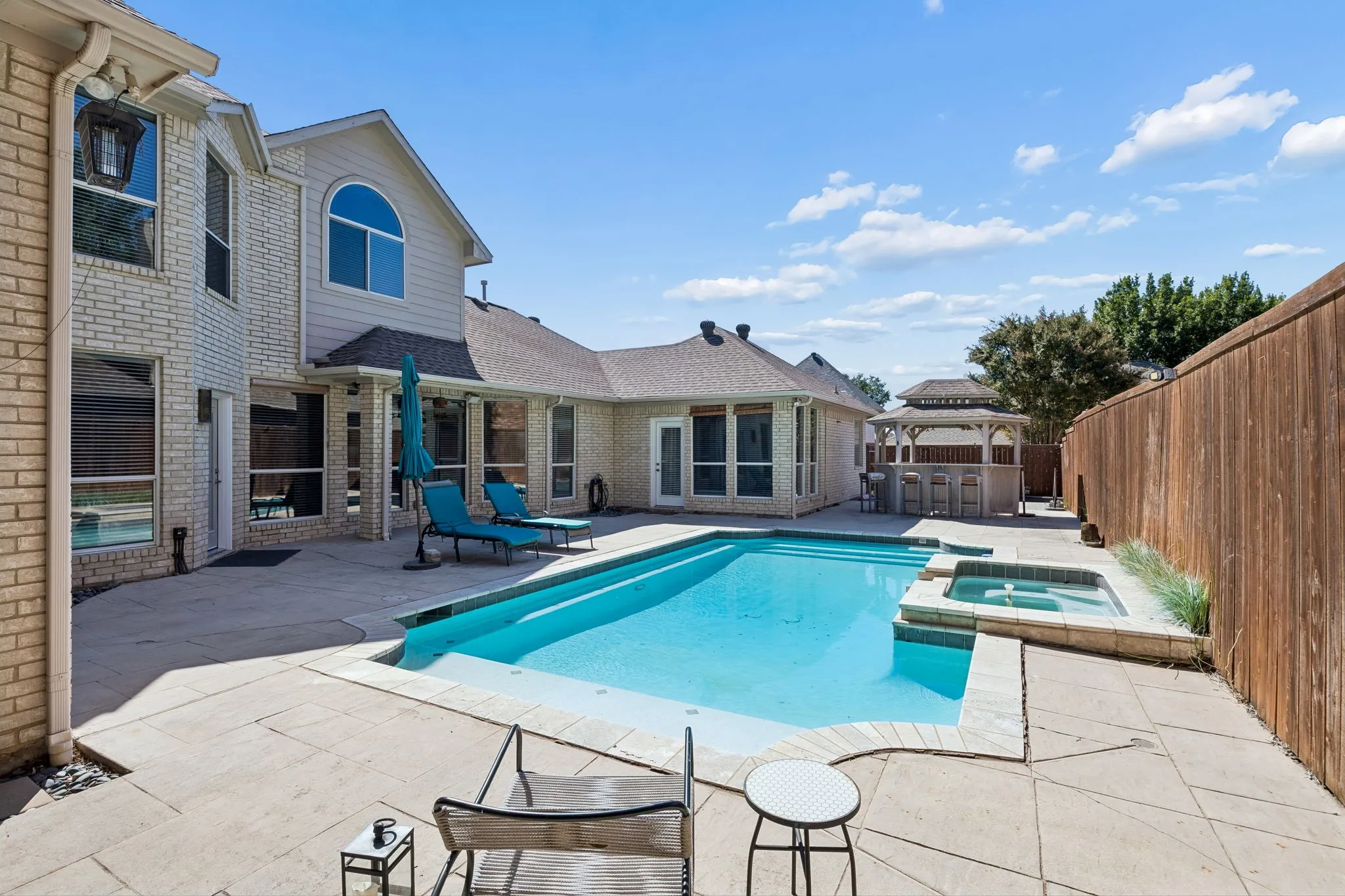 Outdoor swimming pool with integrated spa and surrounding concrete patio