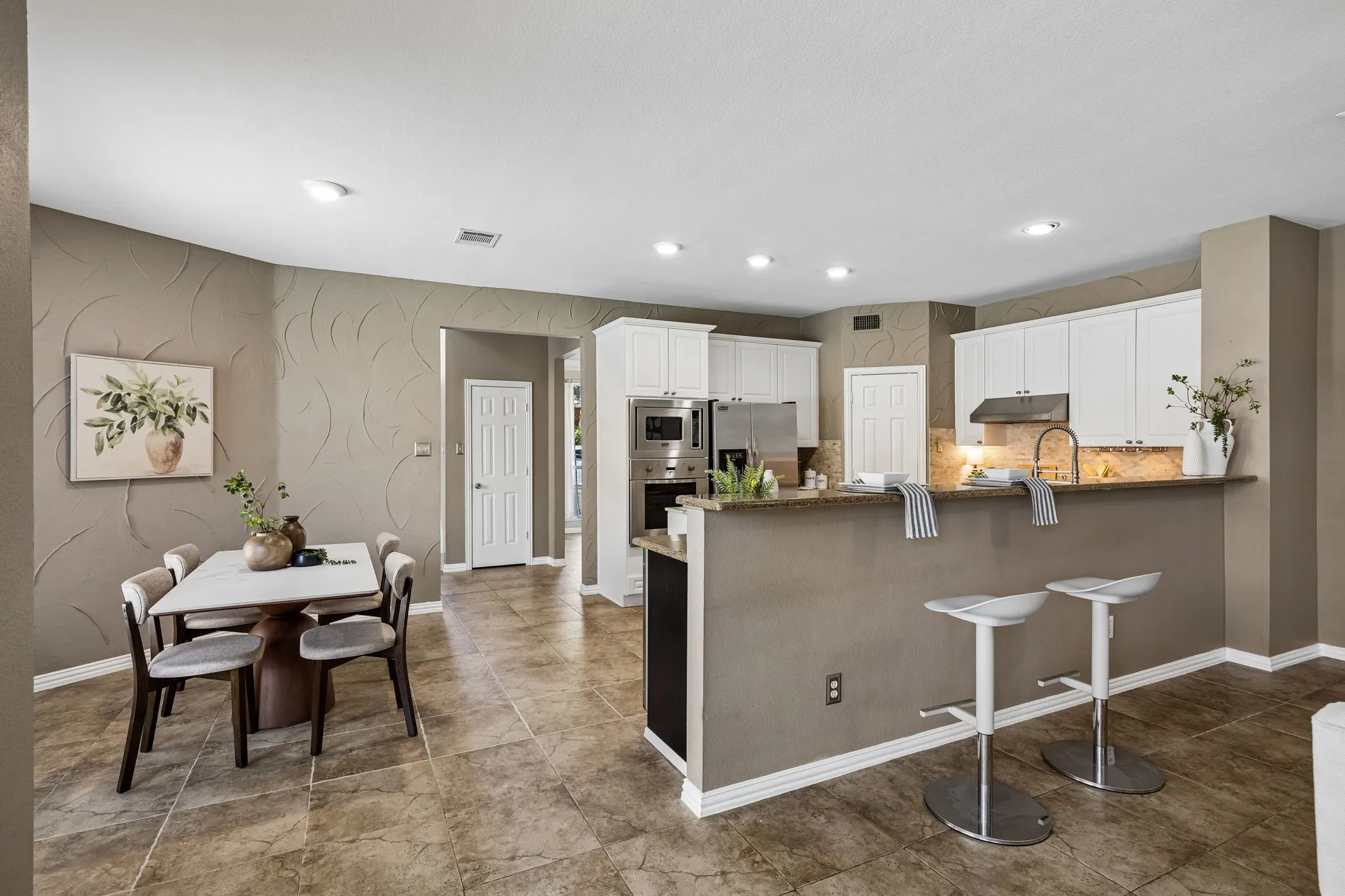 Kitchen featuring white cabinetry, stainless steel appliances, a stone-finish countertop, and tile flooring