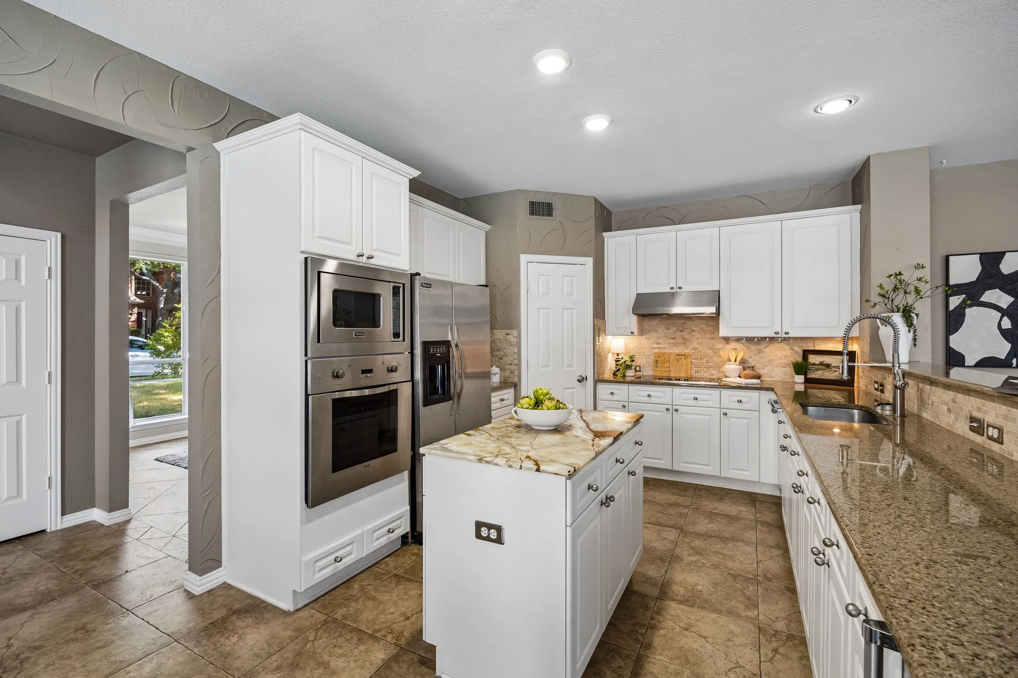 Spacious kitchen featuring white cabinetry, stainless steel appliances, a center island with counter seating, granite countertops, and recessed lighting