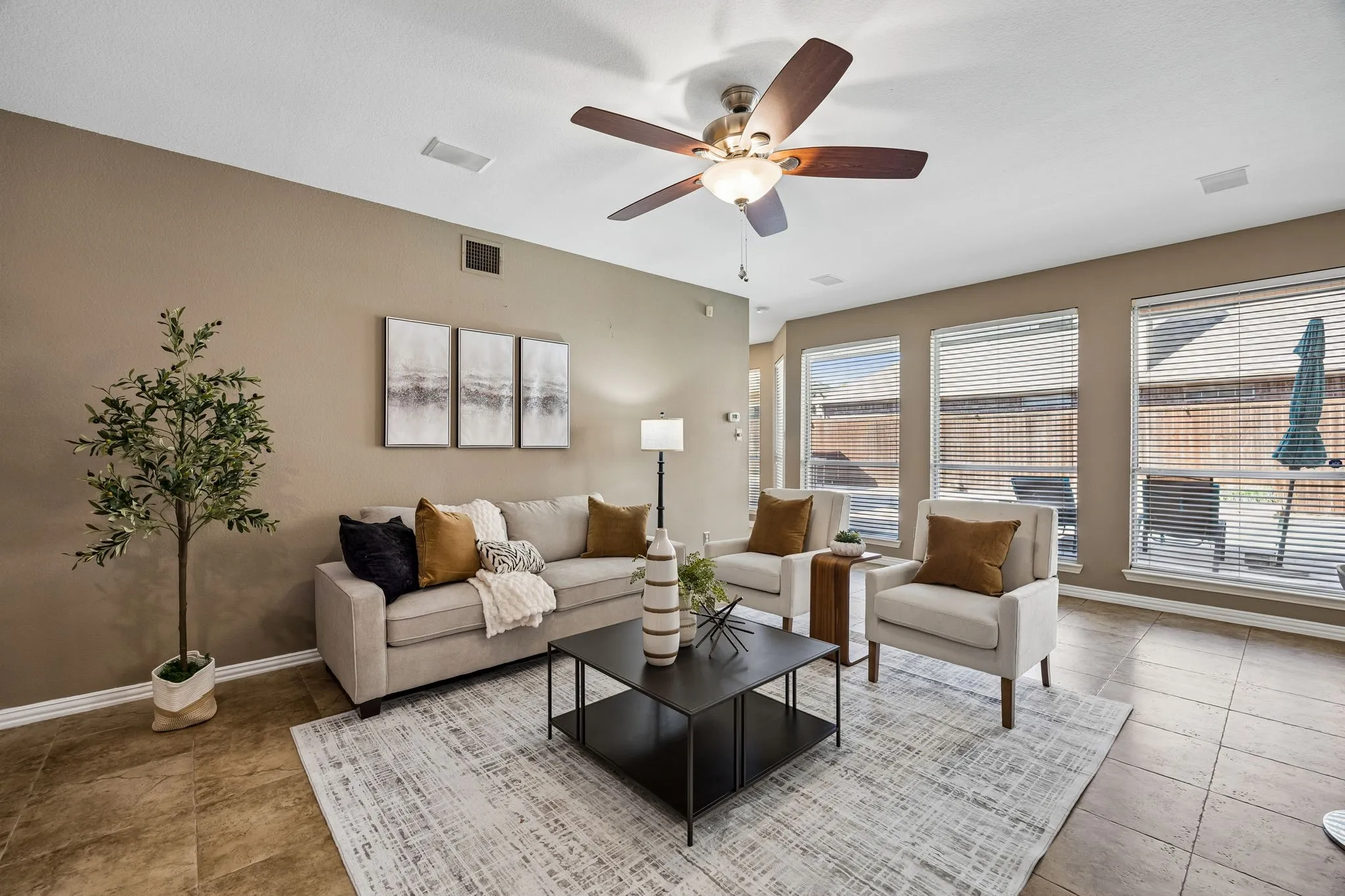 Tile flooring throughout, neutral painted walls, ceiling fan, and multiple windows with blinds