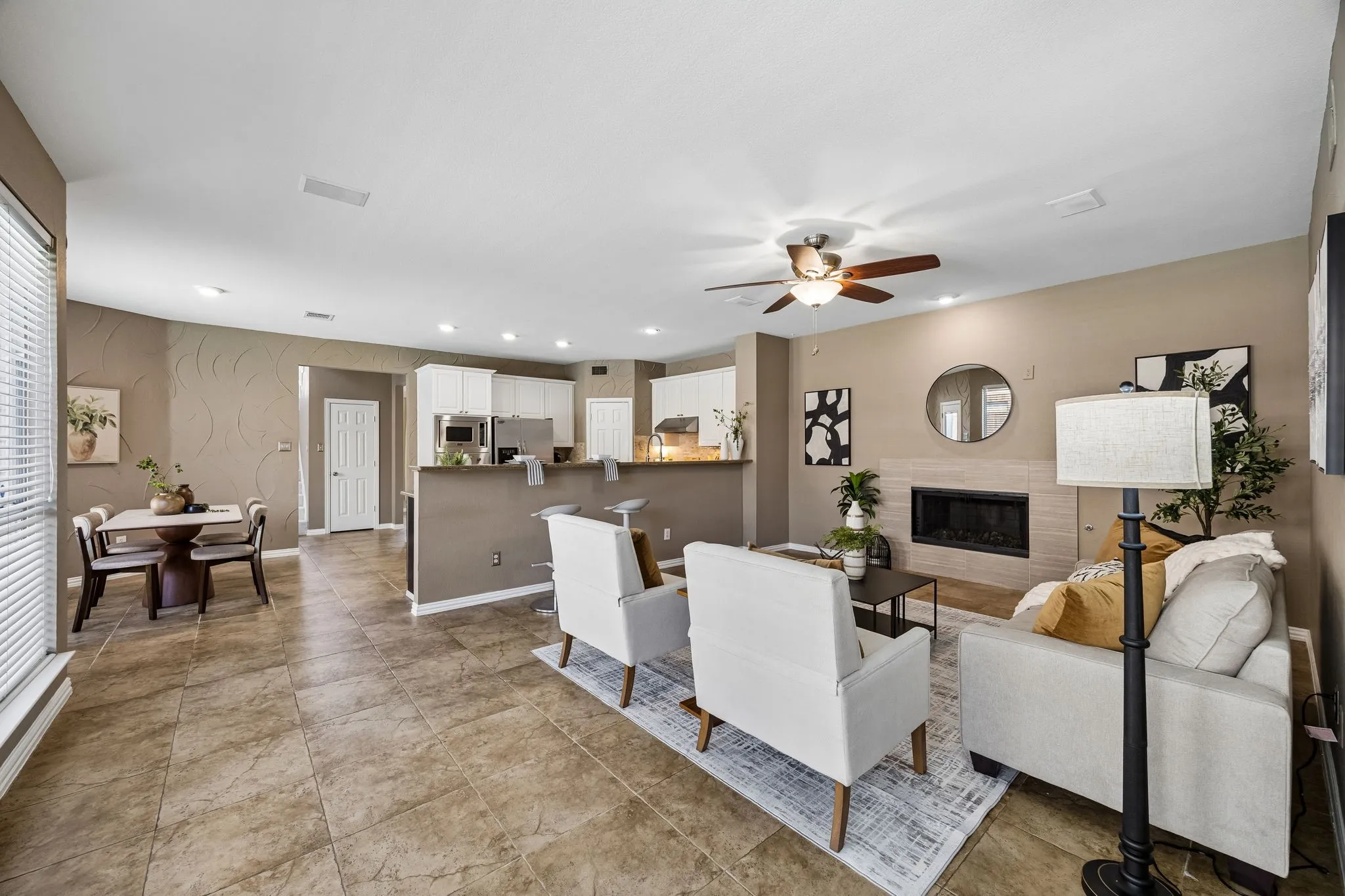 Open-concept living space featuring a fireplace, ceiling fan, and tile flooring