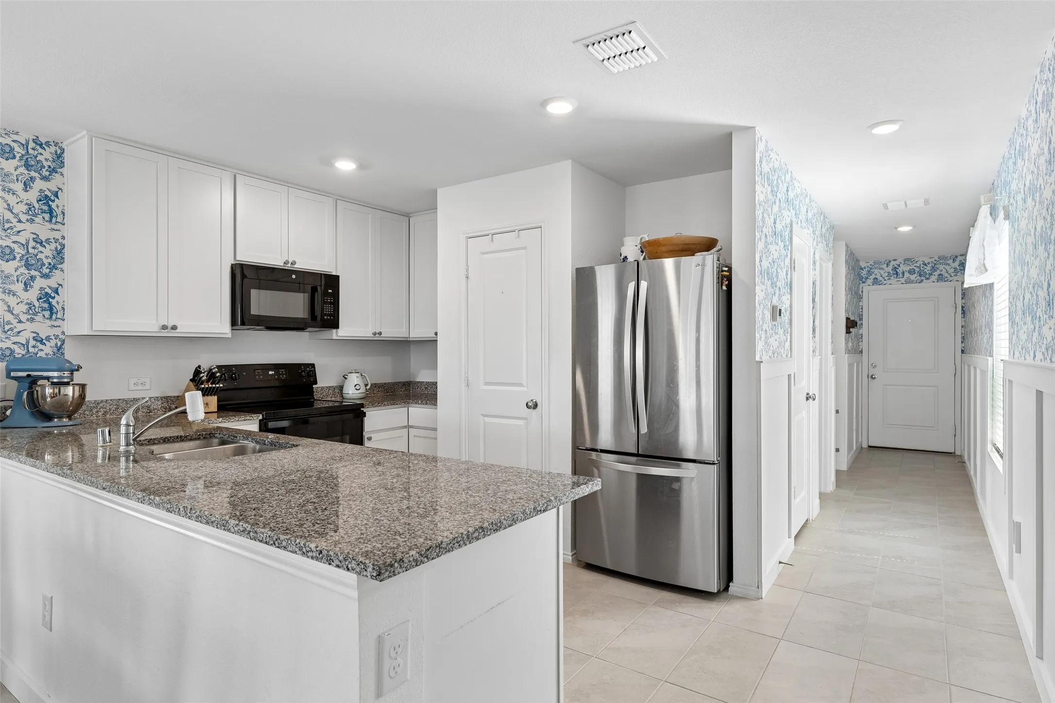 Kitchen featuring white cabinetry, granite countertops, and a full suite of appliances