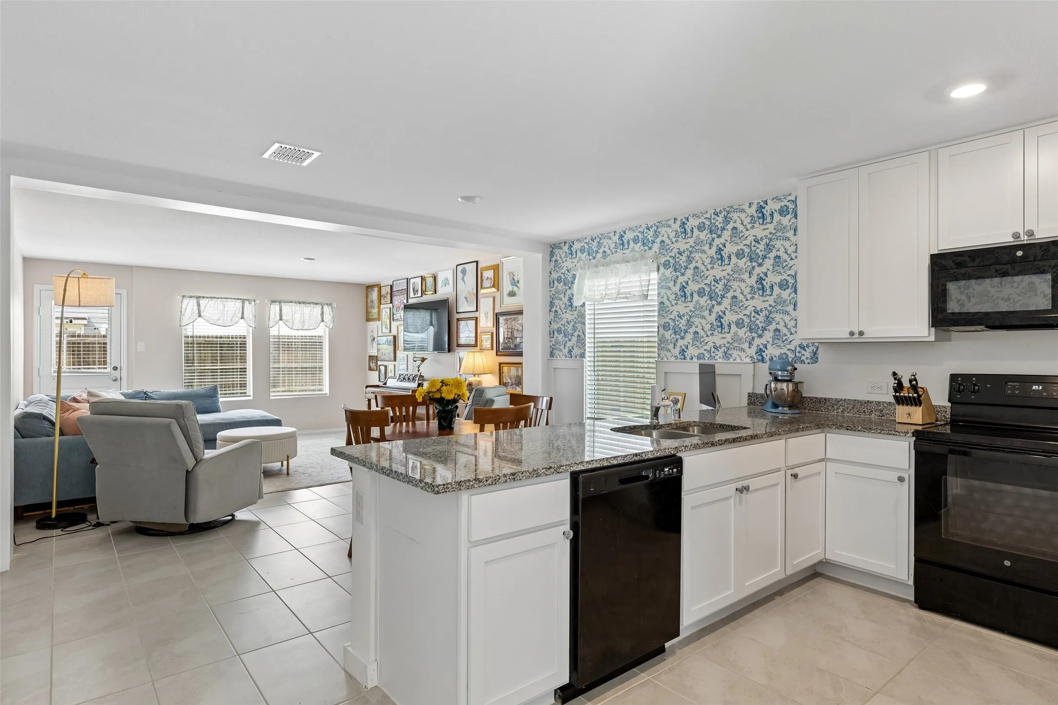 Kitchen featuring white cabinetry, black appliances, and granite countertops