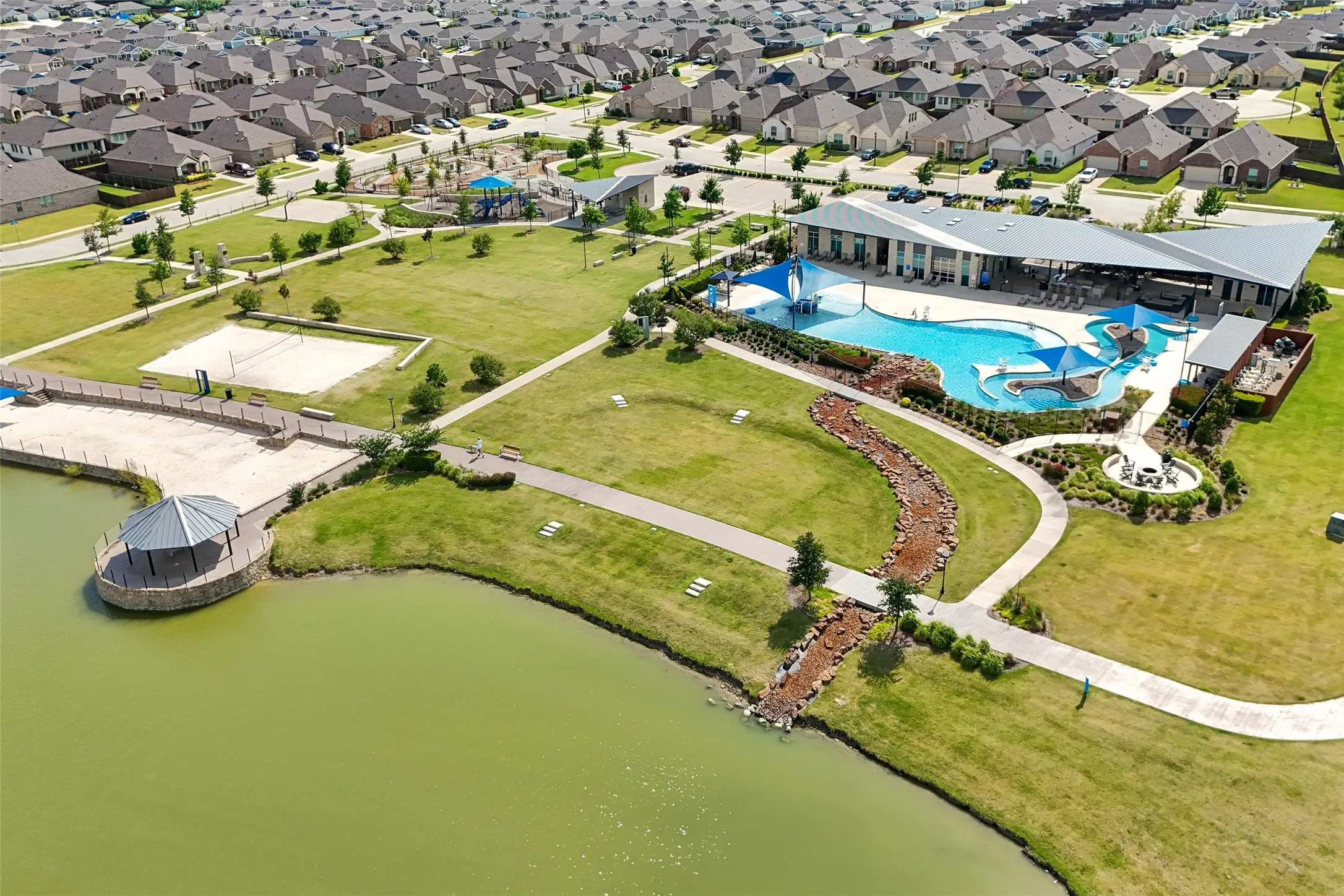 Community amenities featuring a large aquatic center, recreational pool, sand volleyball court, and a park with a playground