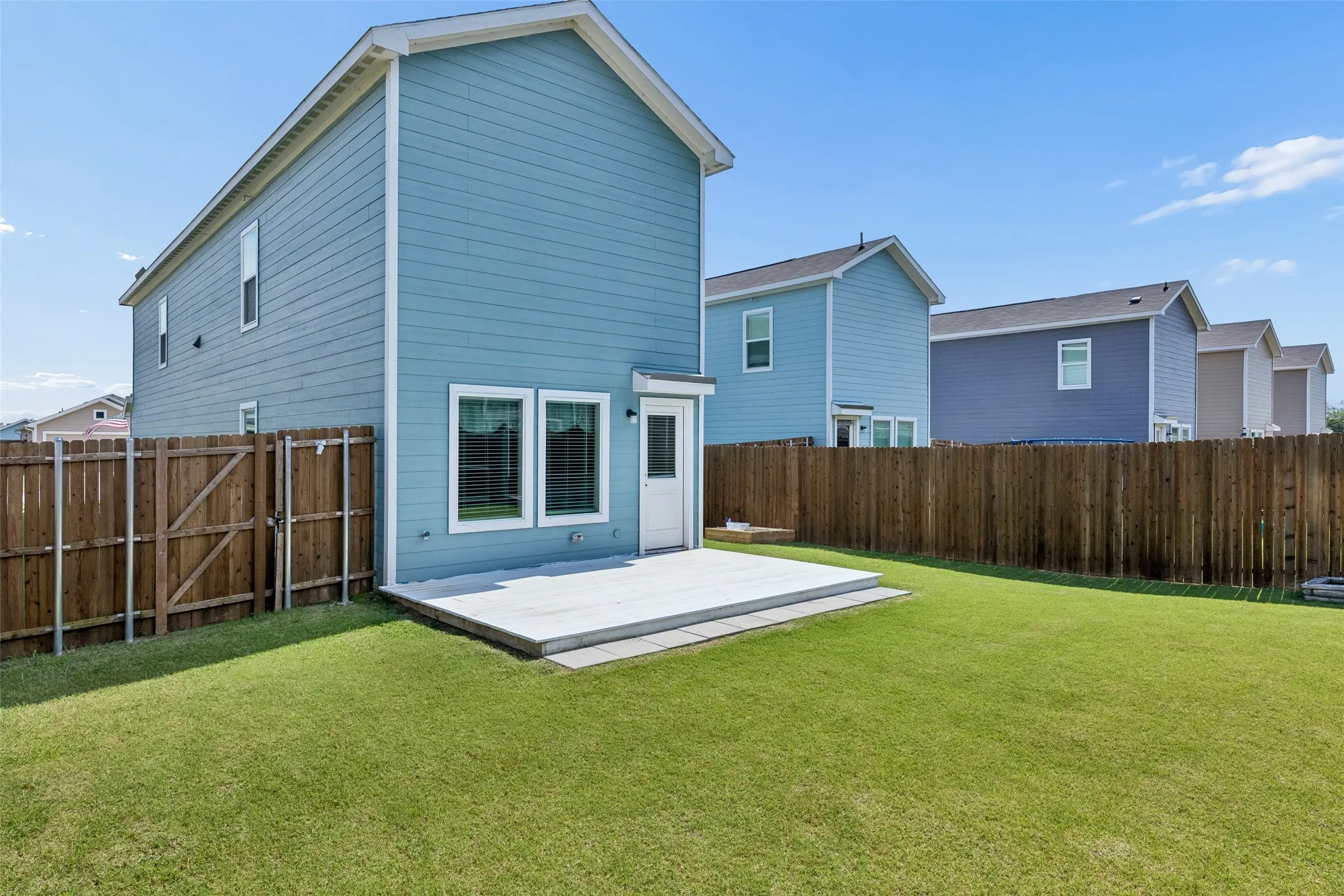 Expansive backyard featuring a manicured lawn, full privacy fencing, and a concrete patio