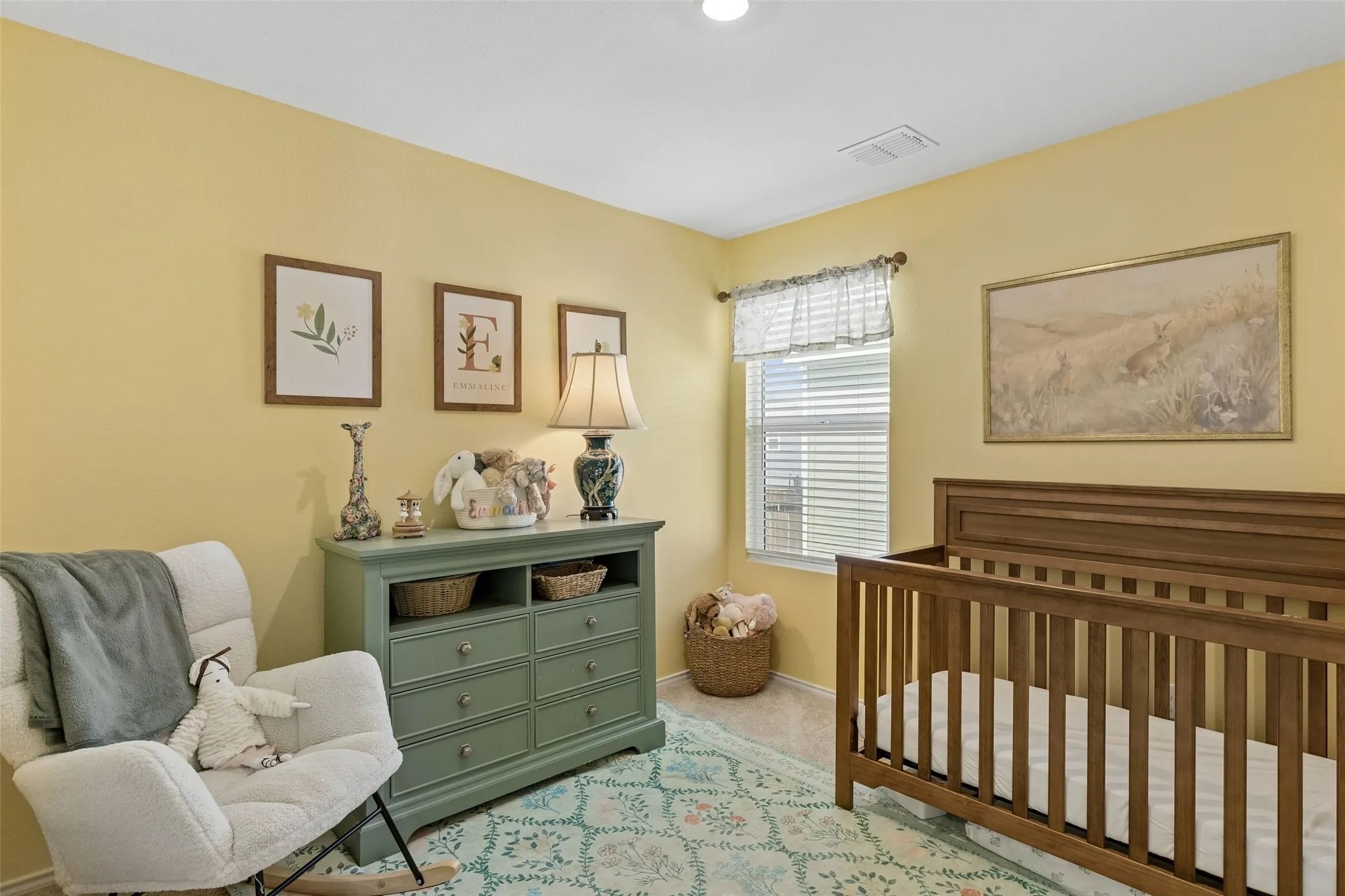 Recessed ceiling lighting, window with blinds, wood-finish crib, and light-colored wall-to-wall carpeting
