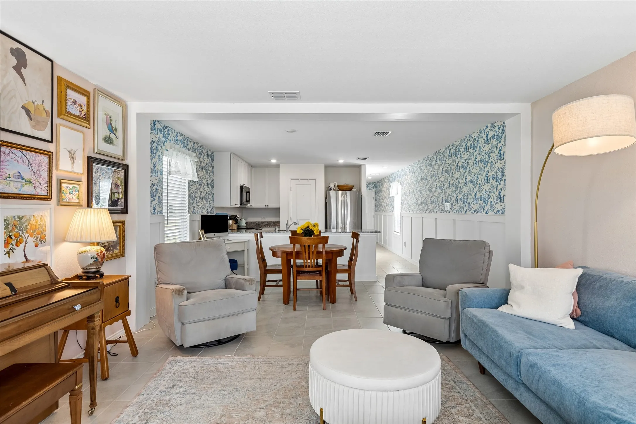 Open-concept living area featuring light-toned tile flooring and white trim