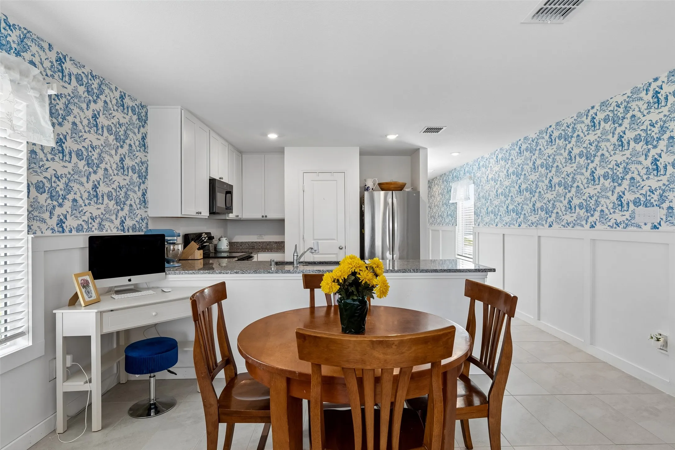 Kitchen with white shaker cabinetry, granite countertops, tile flooring, and integrated desk area