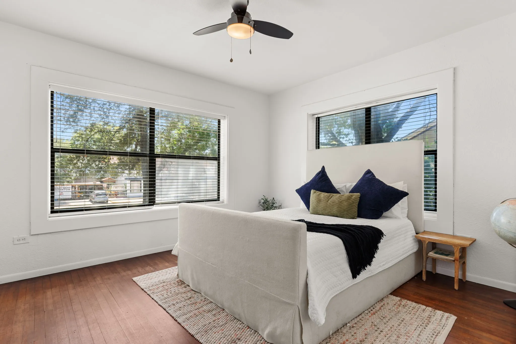 Bright room featuring wood-finish flooring, white walls, and multiple windows with blinds