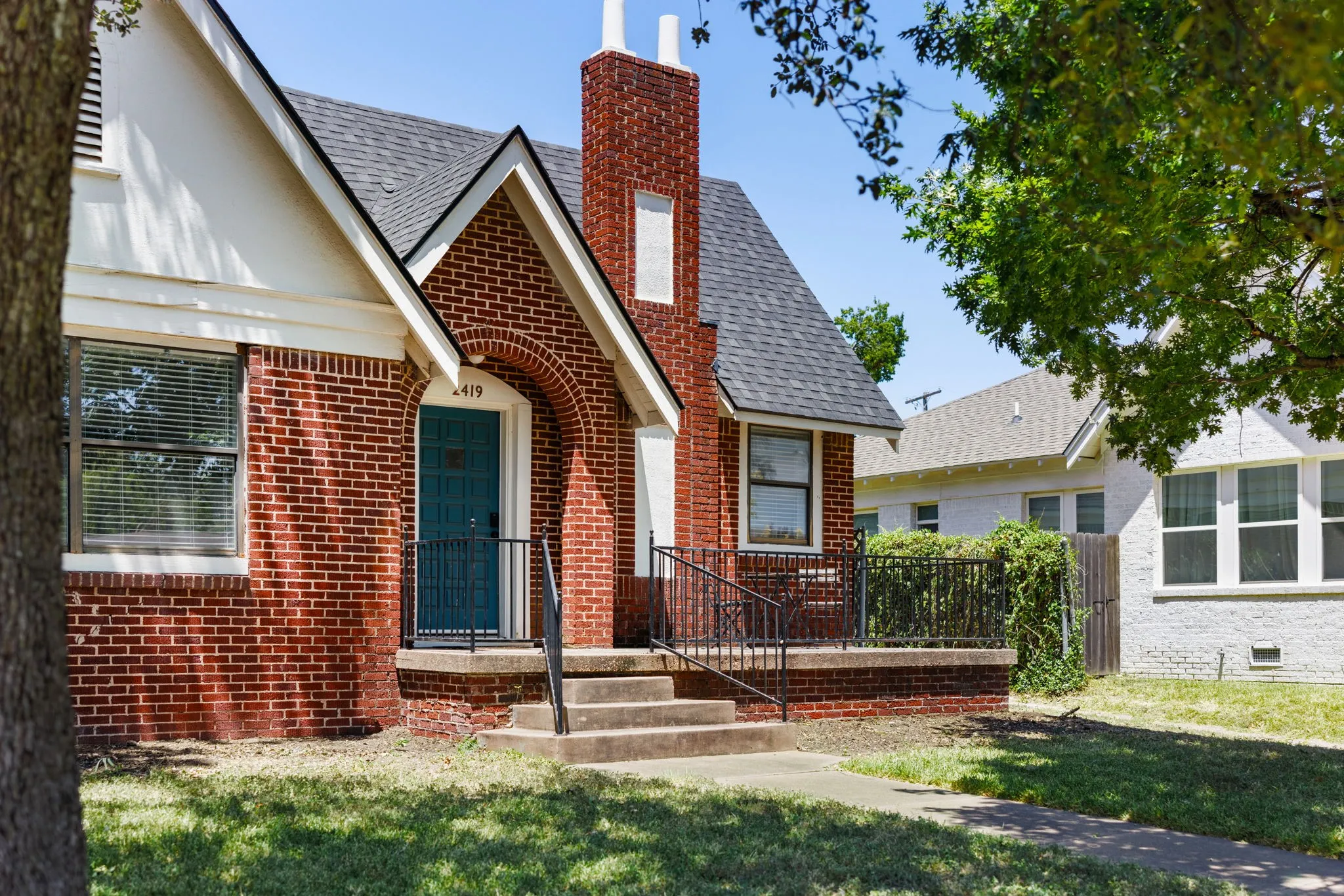 Brick exterior residence featuring a gabled roof, prominent brick chimney, and a covered entry with an arched brick surround