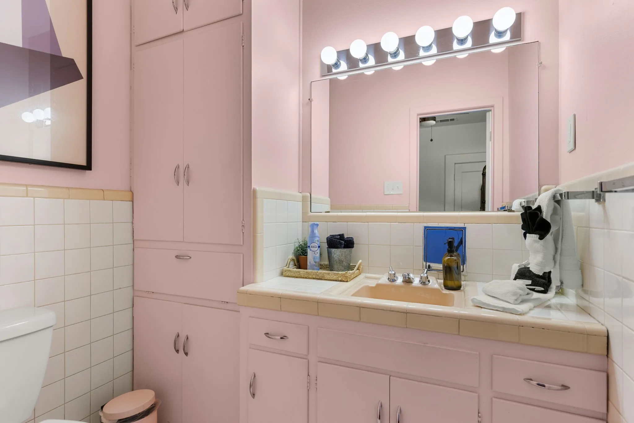 Bathroom featuring a vanity with an integrated sink, tile countertop, and extensive built-in cabinetry