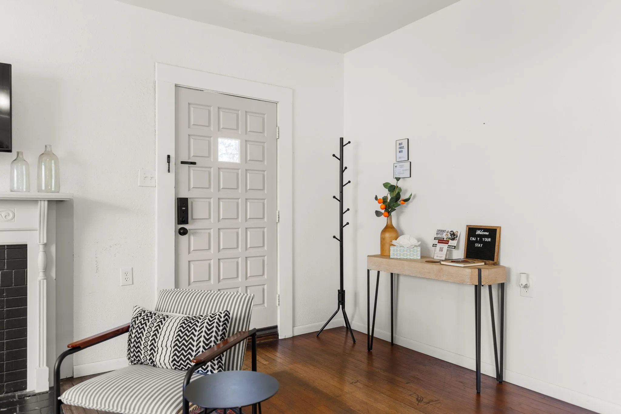 Paneled entry door with frosted glass insert, rich wood-finish flooring, and a decorative fireplace with a mantel
