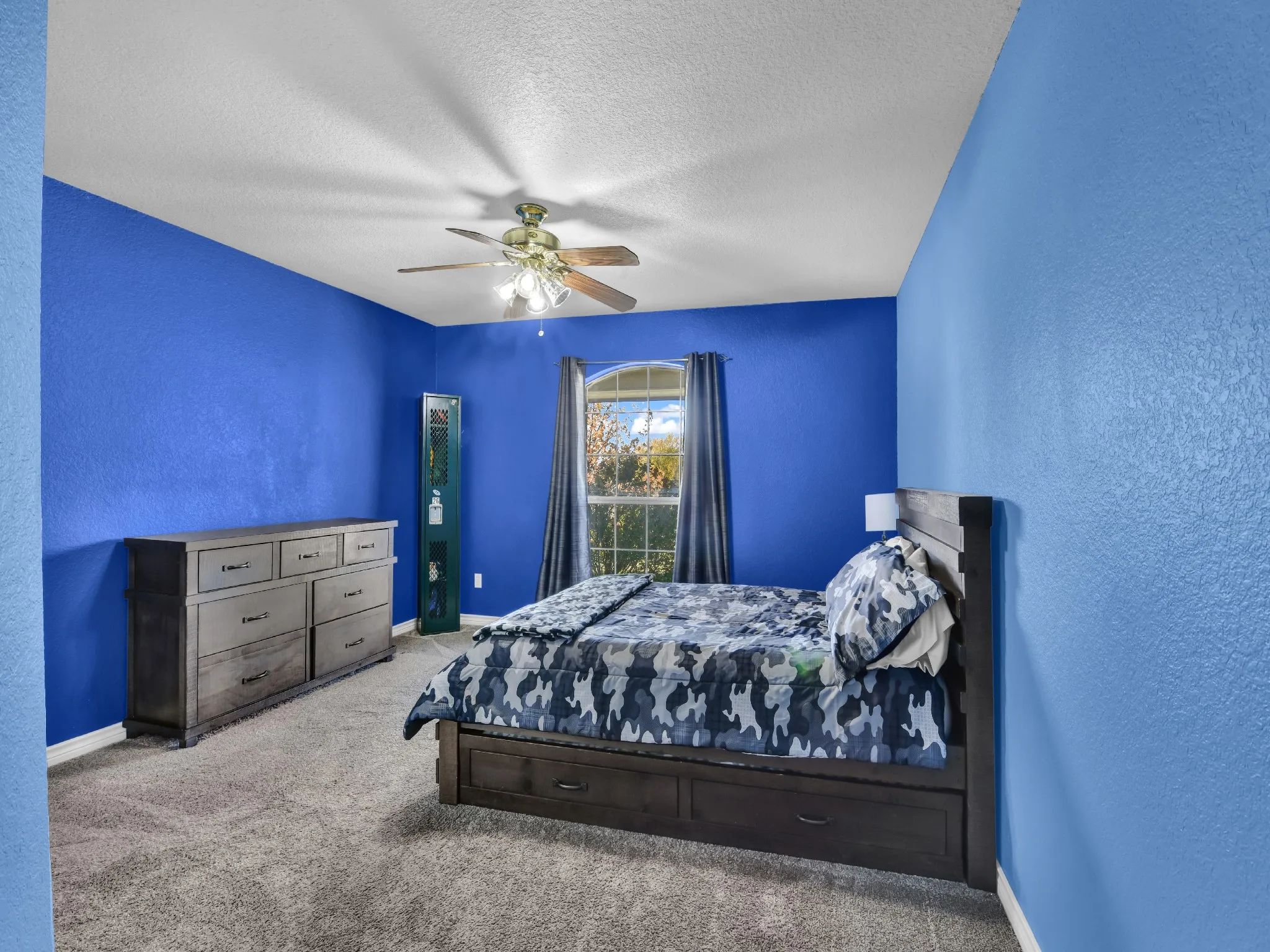 Carpeted flooring, window with curtains, and a ceiling fan with integrated lighting