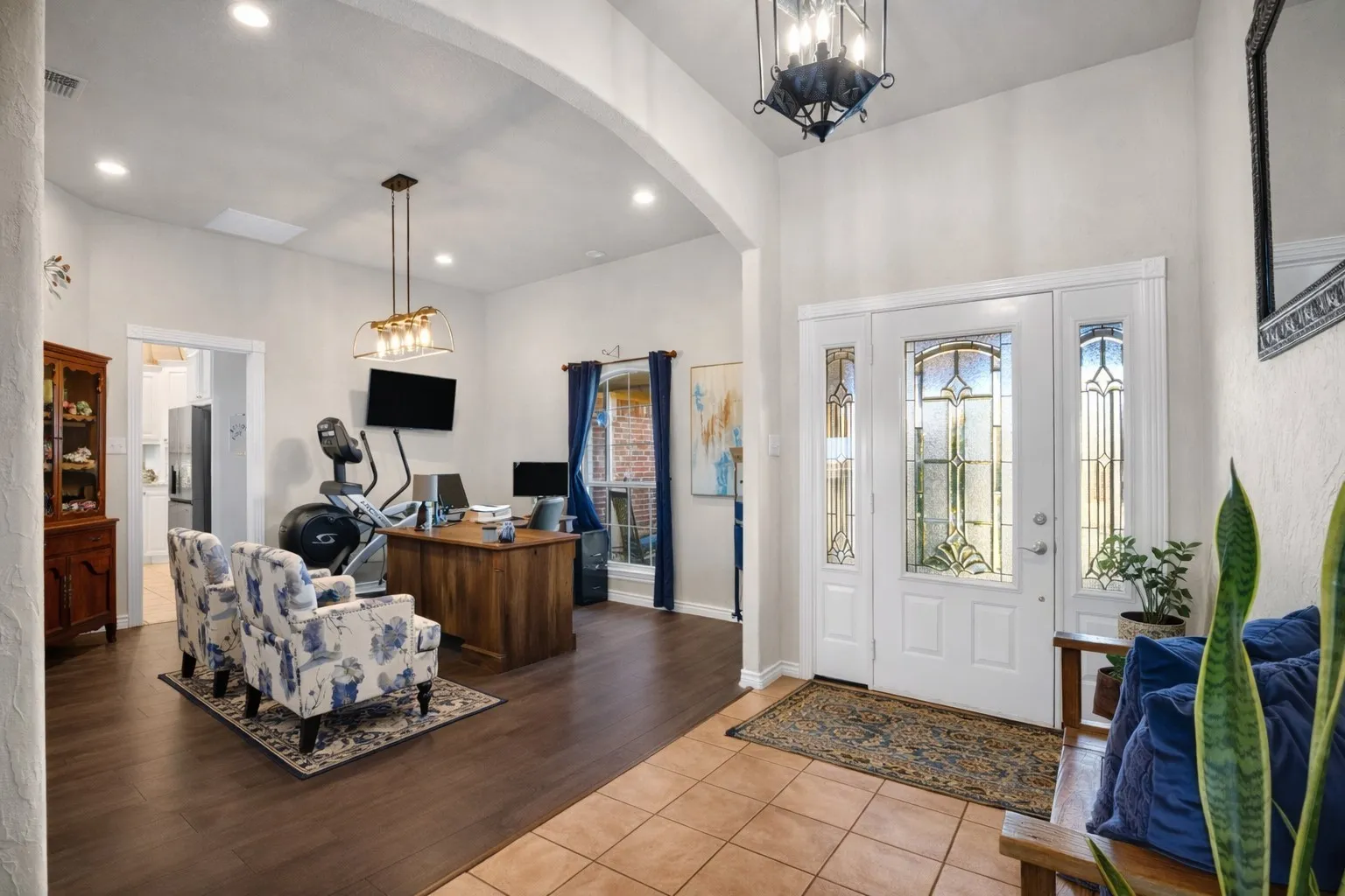 Entryway featuring a decorative glass front door with side panels, a high ceiling, and tile flooring