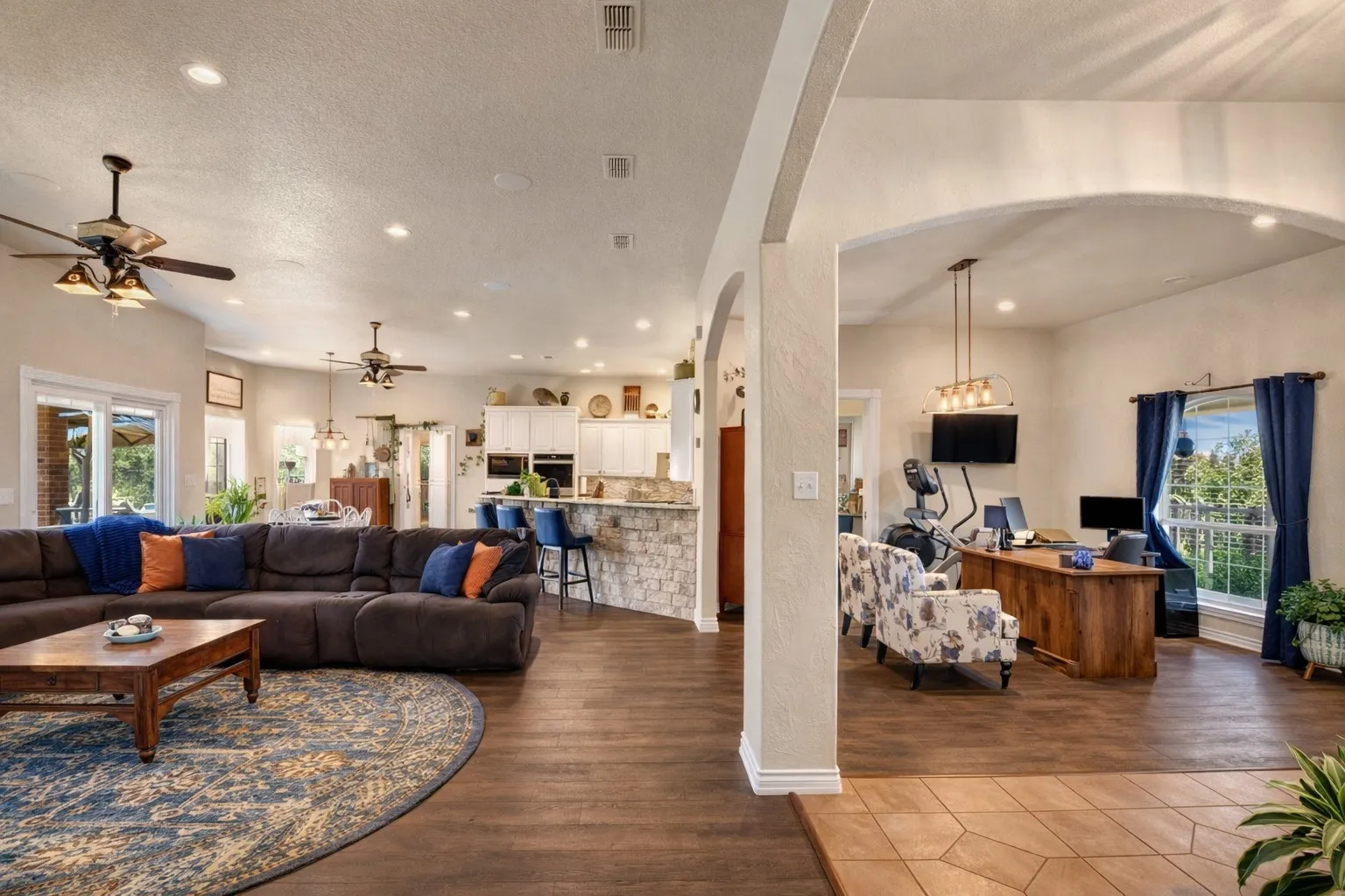 Open-concept living area with wood-finish flooring, recessed lighting, and ceiling fans