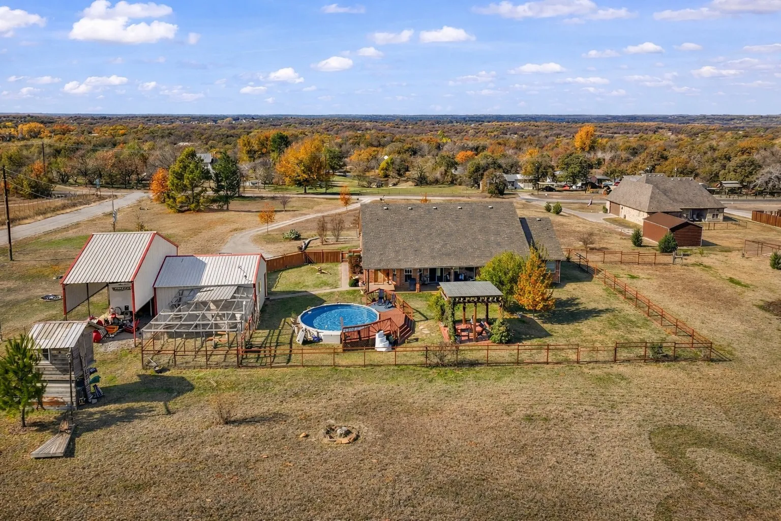 Expansive property featuring a private pool, covered patio, separate outbuilding, and fenced enclosures