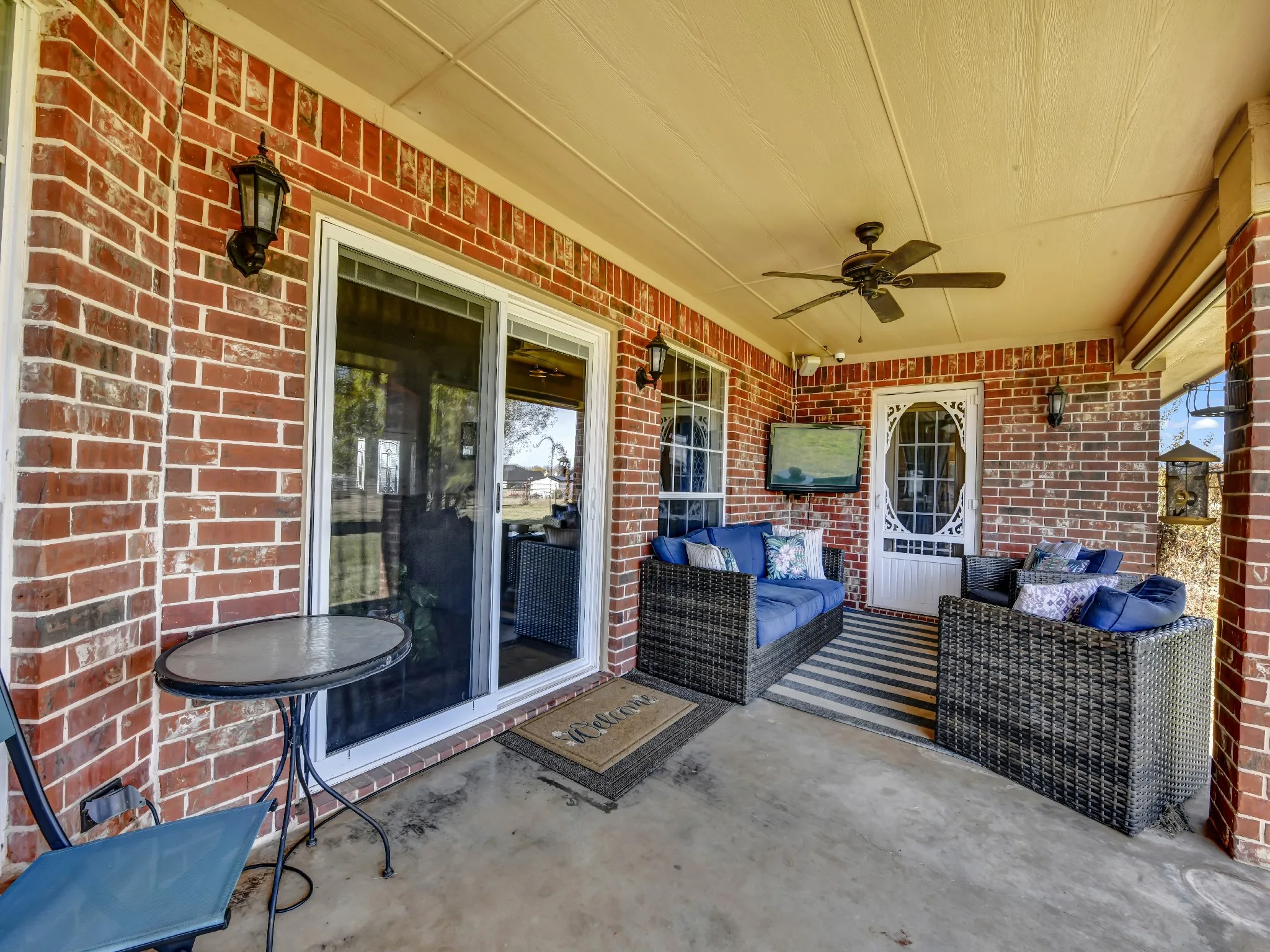 Covered patio with exposed brick walls, ceiling fan, and concrete flooring