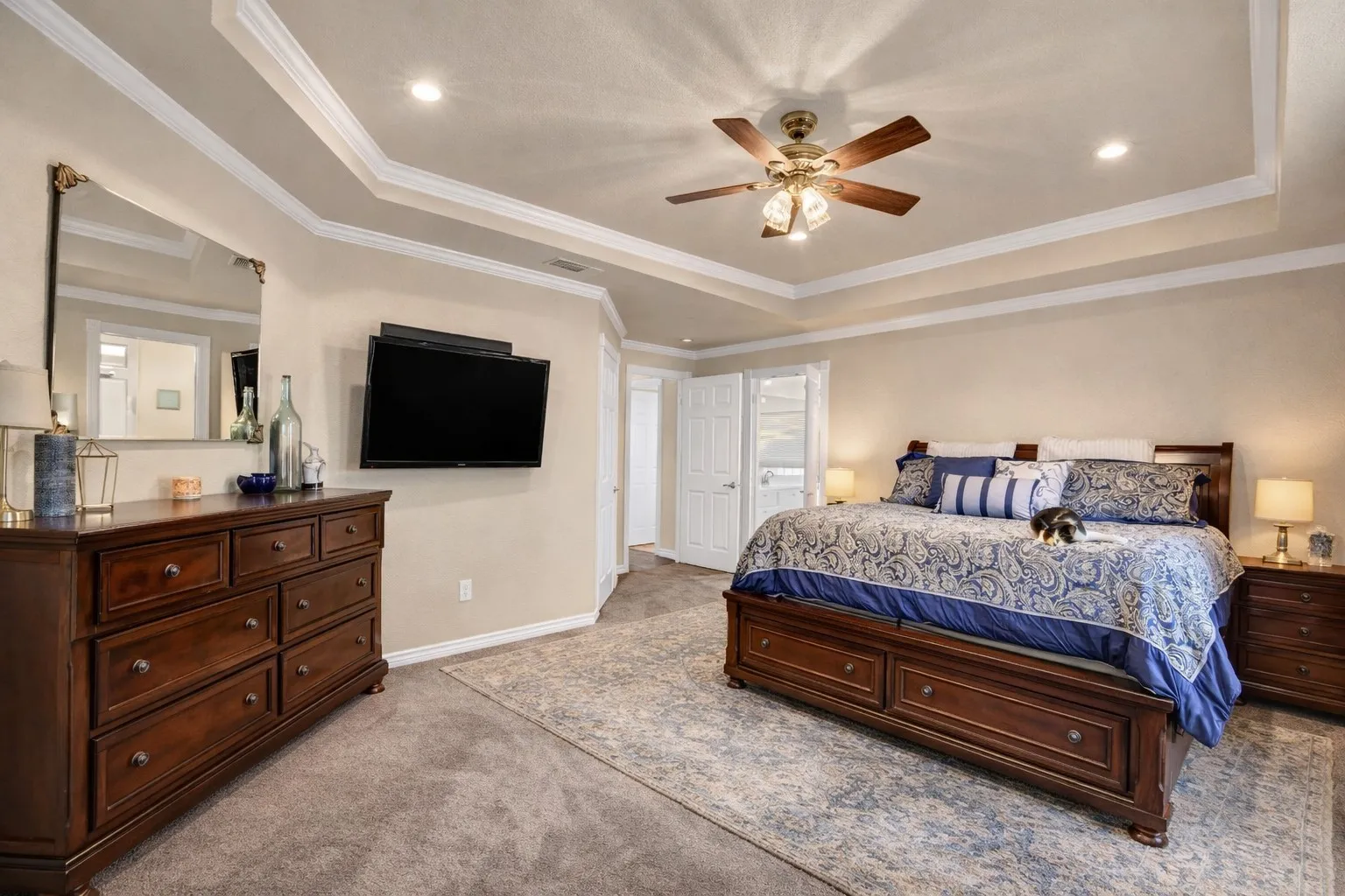 Tray ceiling with crown molding, recessed lighting, ceiling fan, and carpeted flooring