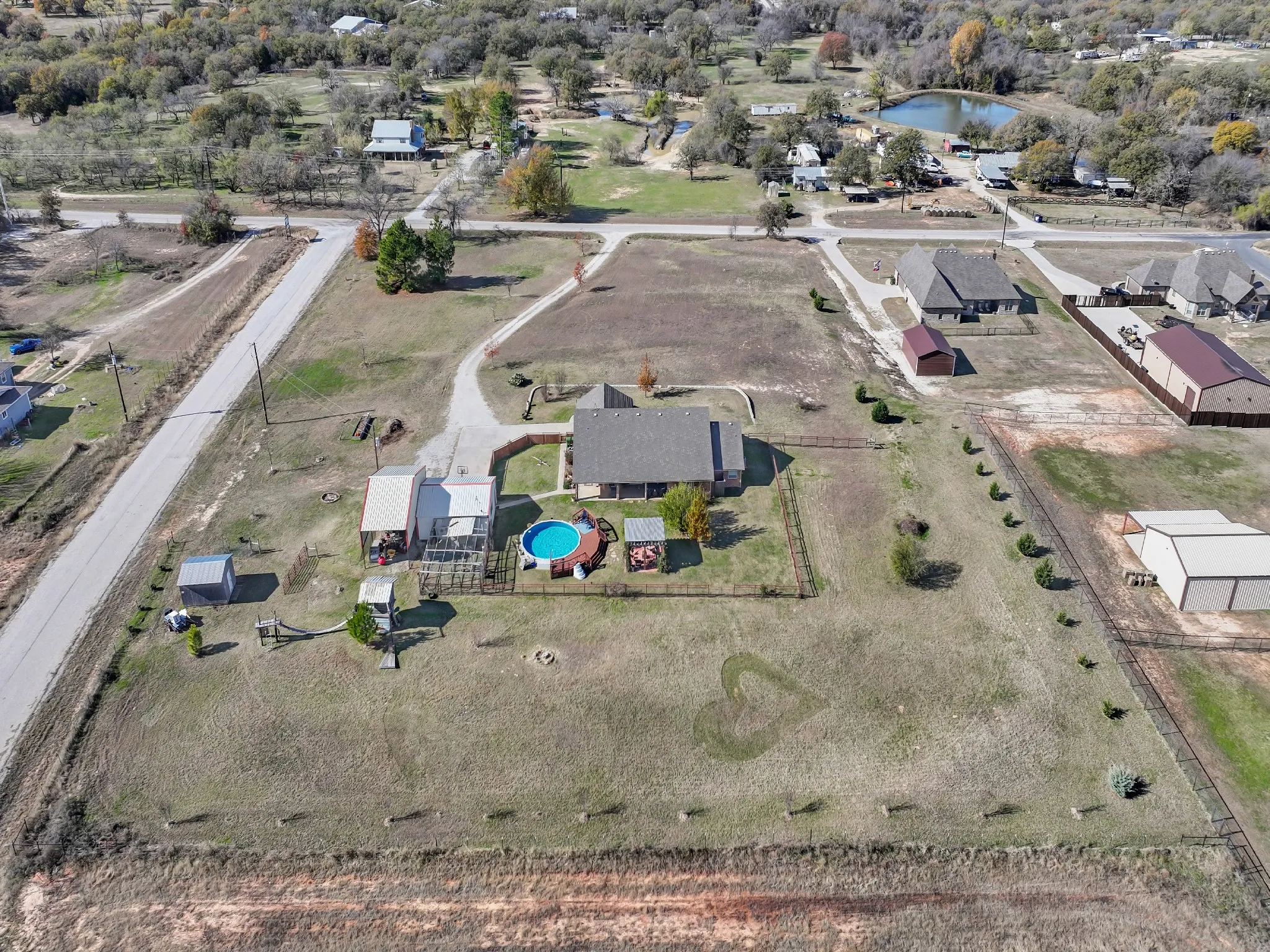 Expansive property with a residential structure, detached outbuildings, a fenced pool, and paved driveways