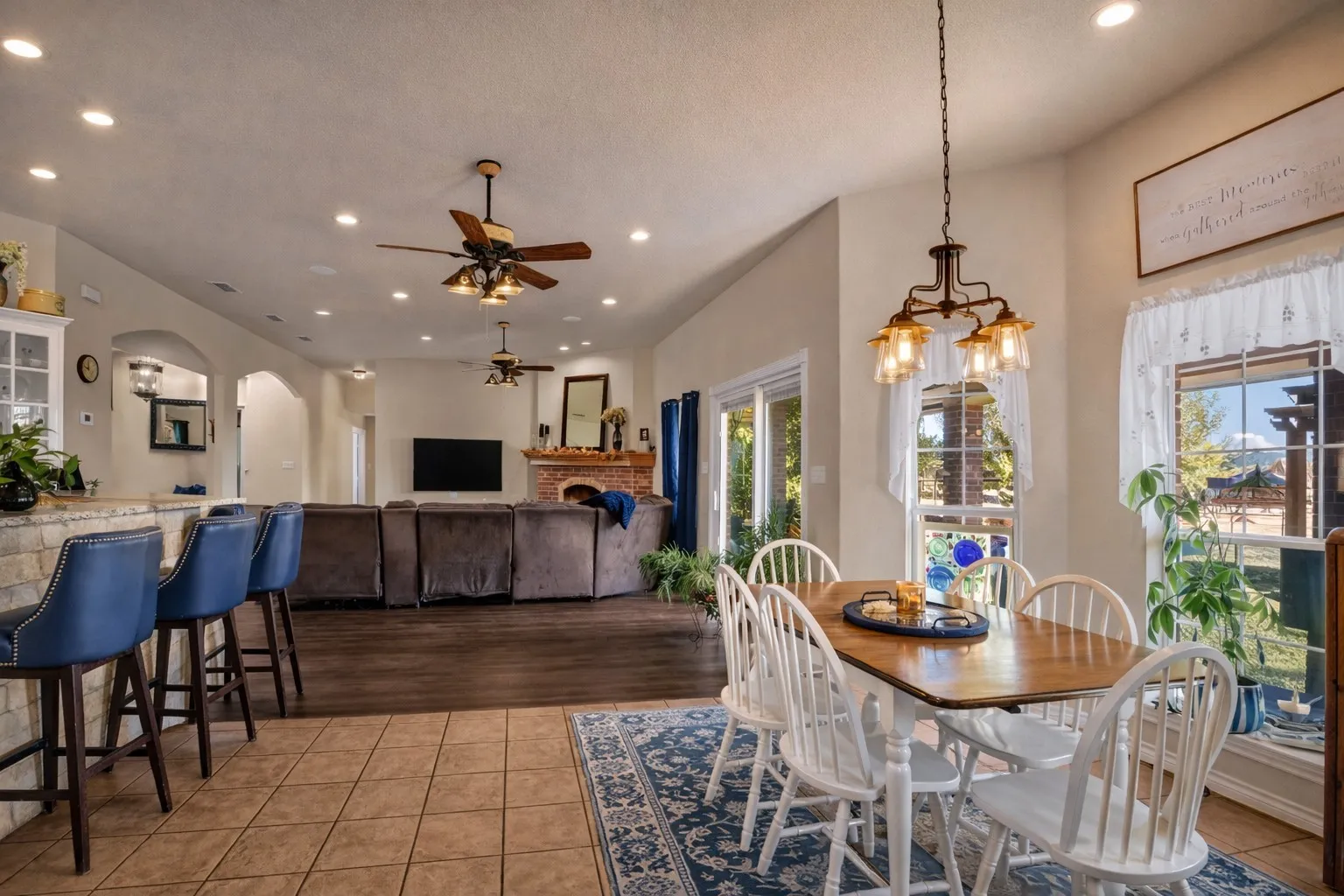 Vaulted ceilings with recessed lighting, brick fireplace, wood-finish flooring, tiled flooring, and a kitchen island with stone-finish surfacing
