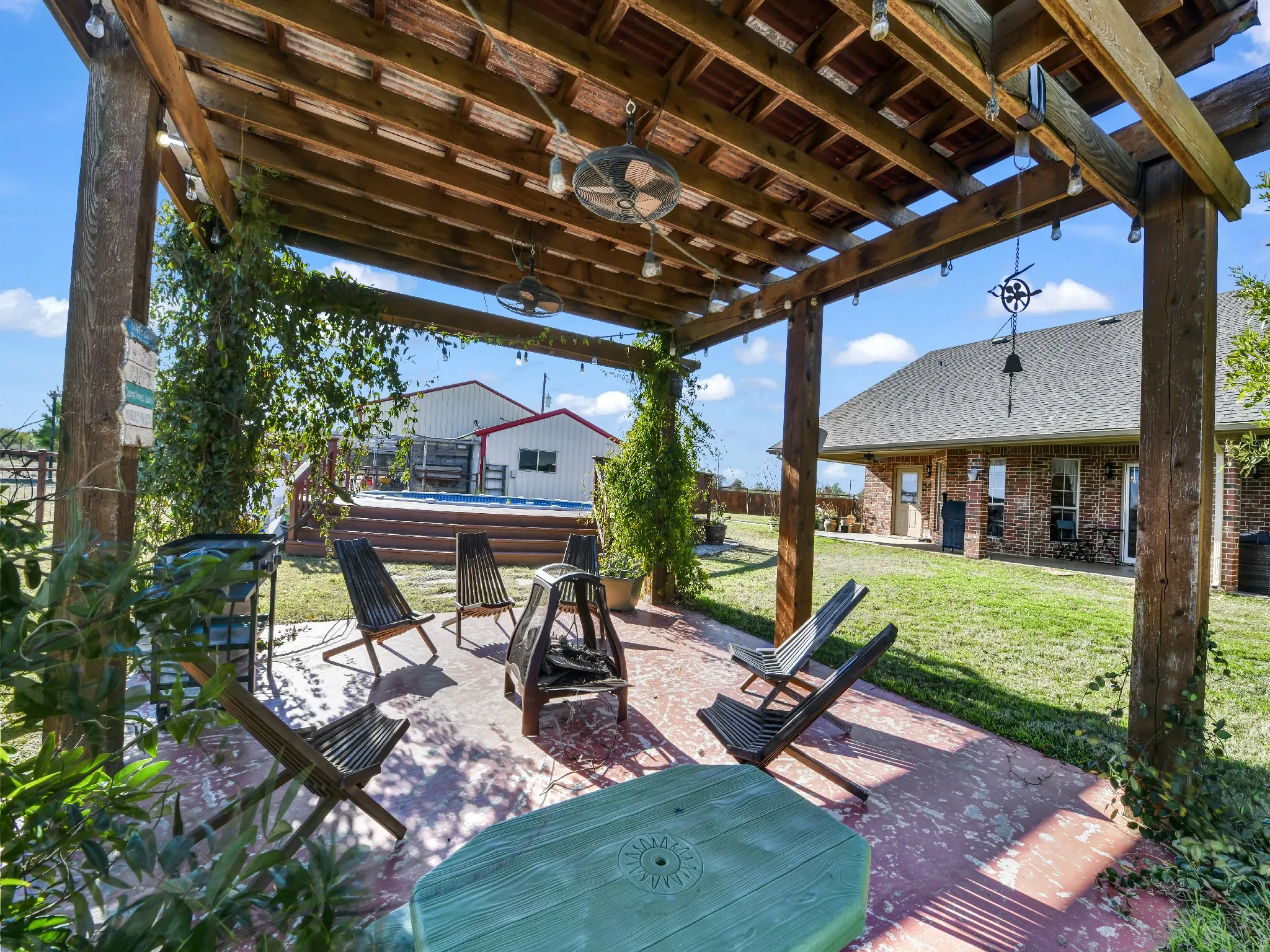 Spacious outdoor patio with a wooden pergola, string lighting, and ceiling fans