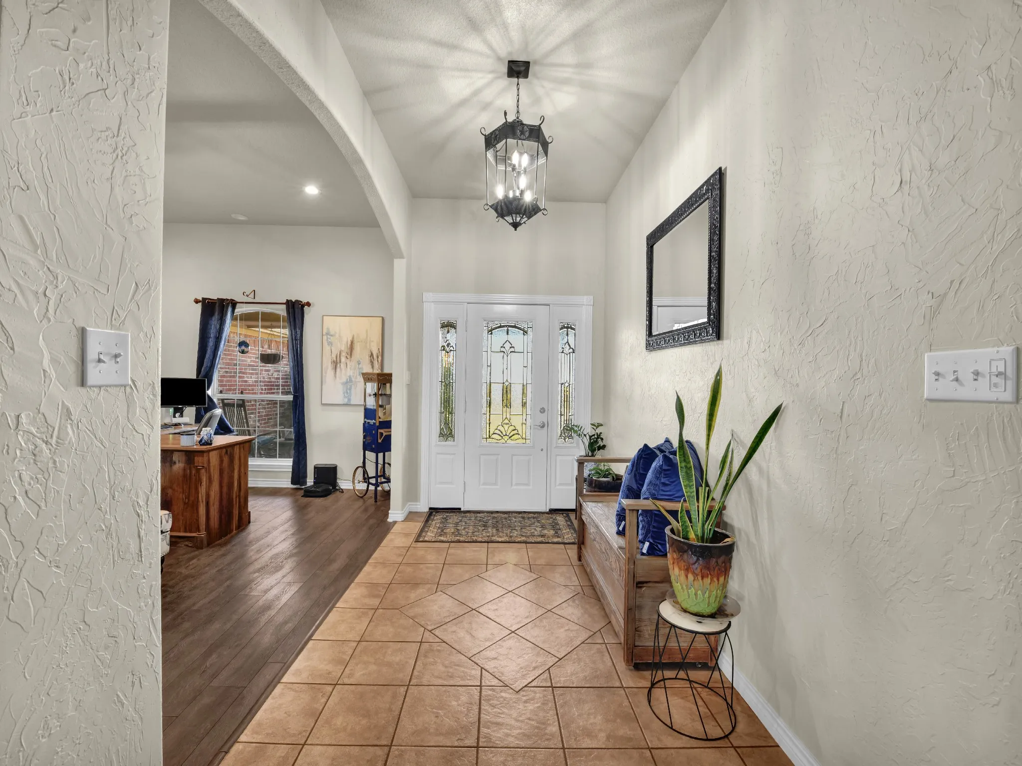 Entryway featuring a decorative pendant light, leaded glass front door, textured wall finishes, and a tile floor