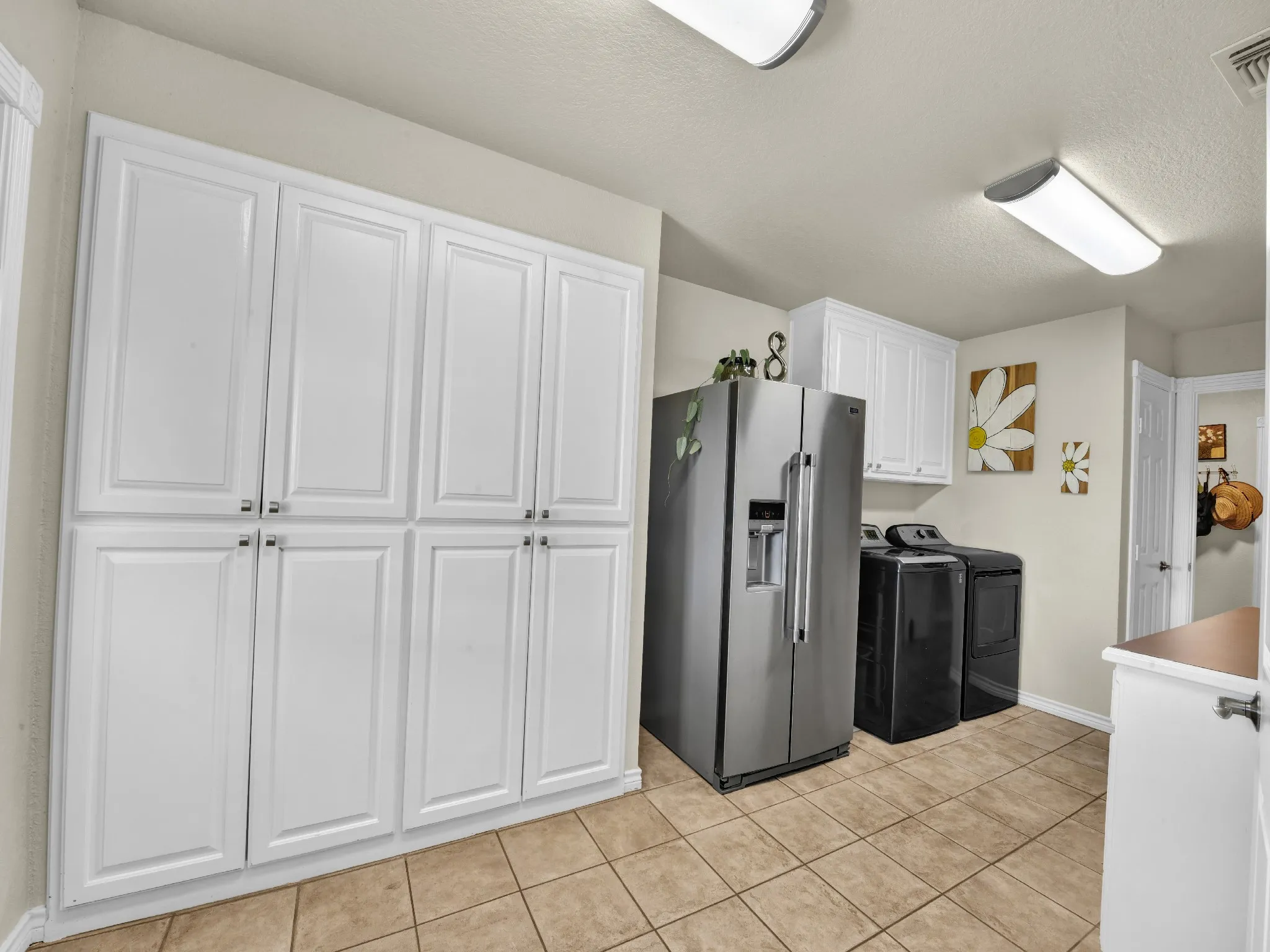 Built-in white cabinetry, tiled flooring, and flush-mount lighting fixtures