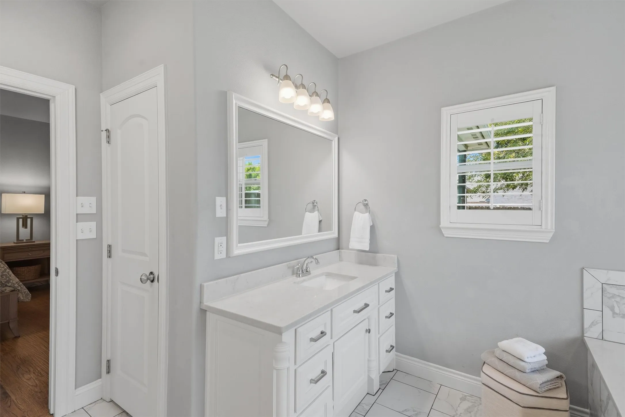 Highlighting dual vanity, ample storage, and plantation shutters to allowing both privacy and extra natural lighting.
