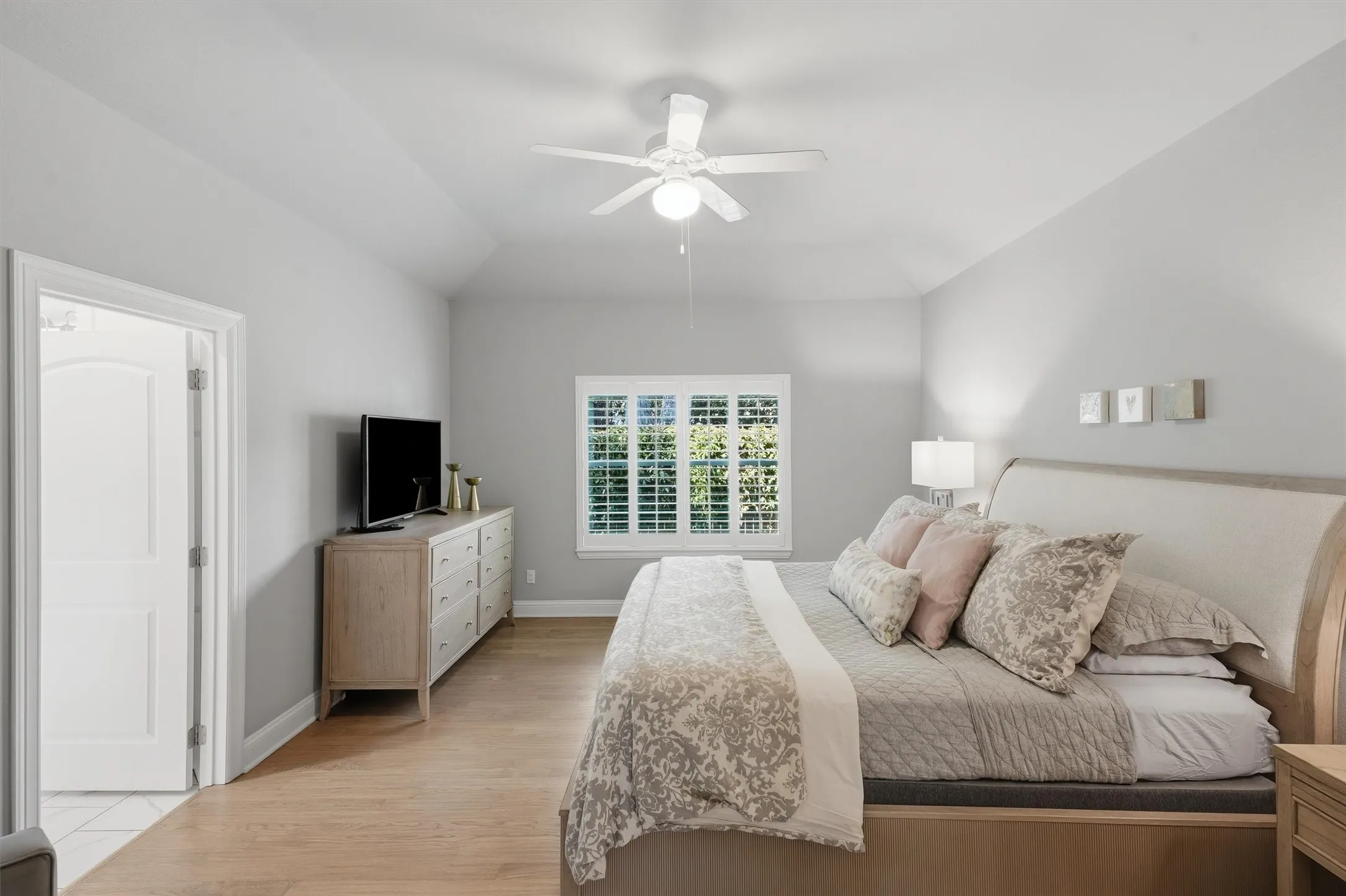 An alternate angle highlights the spaciousness of the primary bedroom, showcasing high vaulted ceilings and an en-suite bathroom entrance.