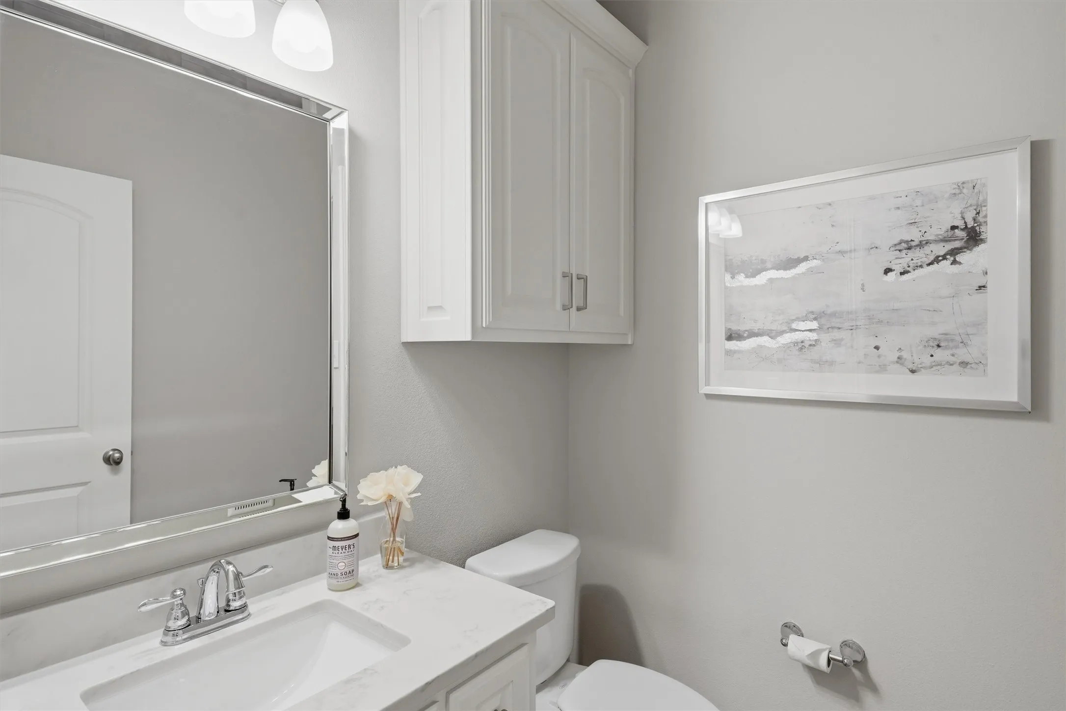 Ideally positioned off the main living area, this half bath is perfectly located for guest access without disturbing nearby bedrooms. Crisp white cabinetry, light stone counters, and a wall-mounted cabinet provide clean style and convenient storage.