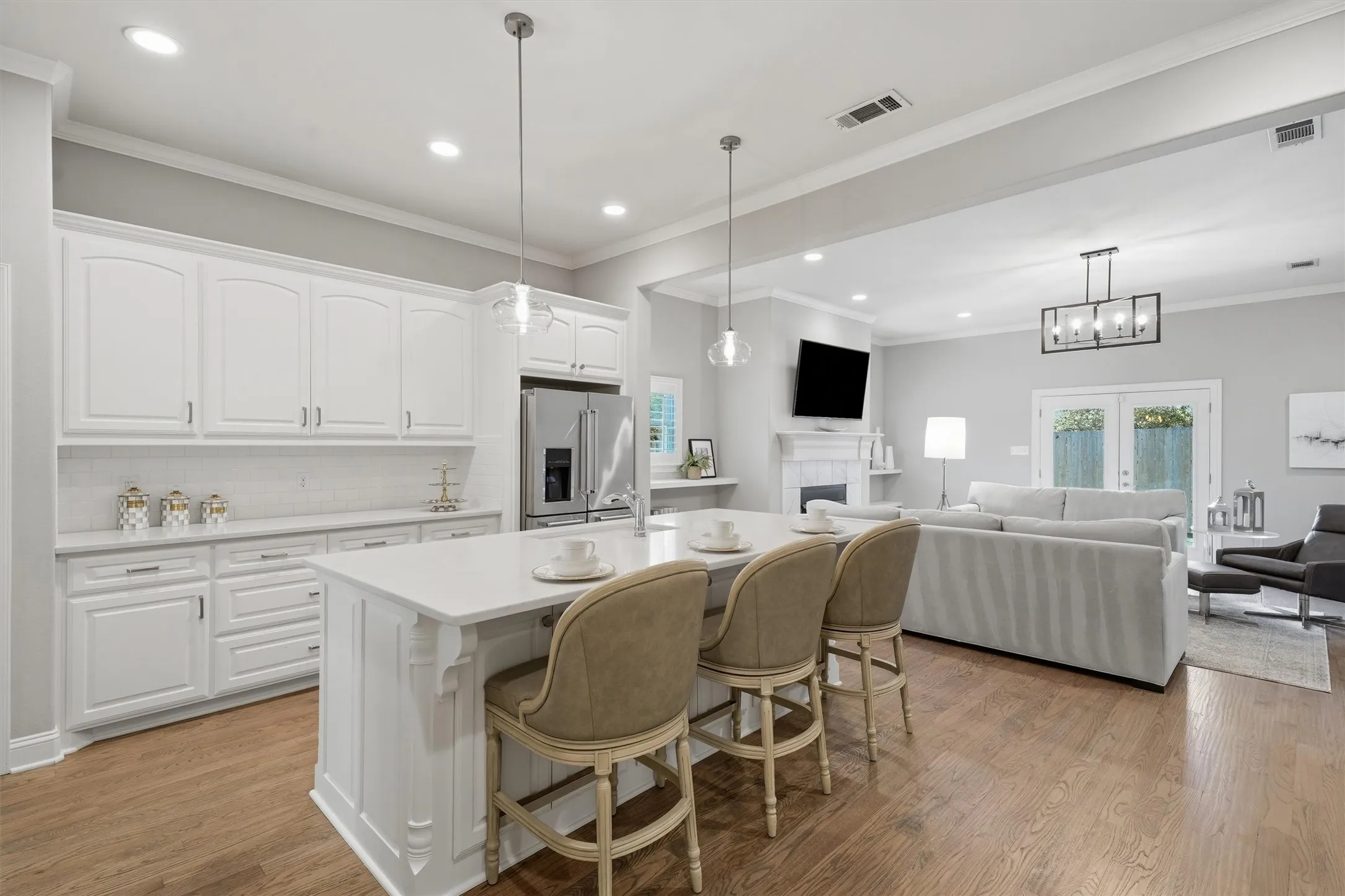 True open-concept layout, highlighting the seamless flow between the kitchen island and main living room. Generous white counter space, extensive cabinetry, and glass pendant lights make entertaining effortless.