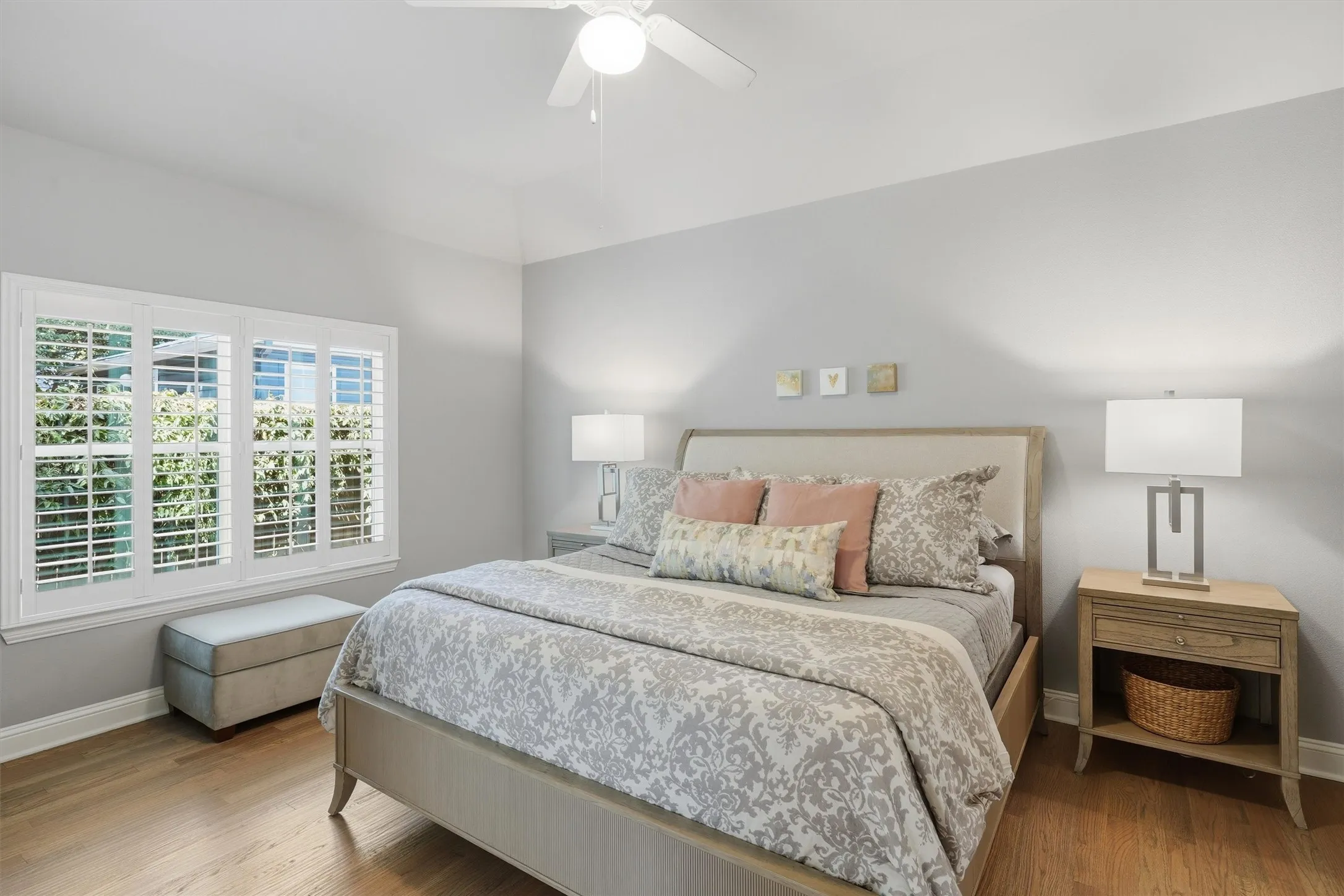The primary suite offers a serene retreat with large windows outfitted with crisp plantation shutters draw in pleasant soft lighting to create an inviting atmosphere.