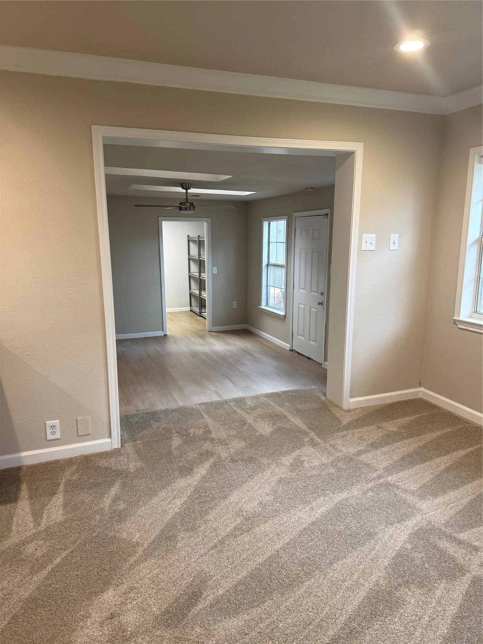Recessed ceiling lighting, crown molding, light-toned wall paint, wood-finish flooring, and a ceiling fan