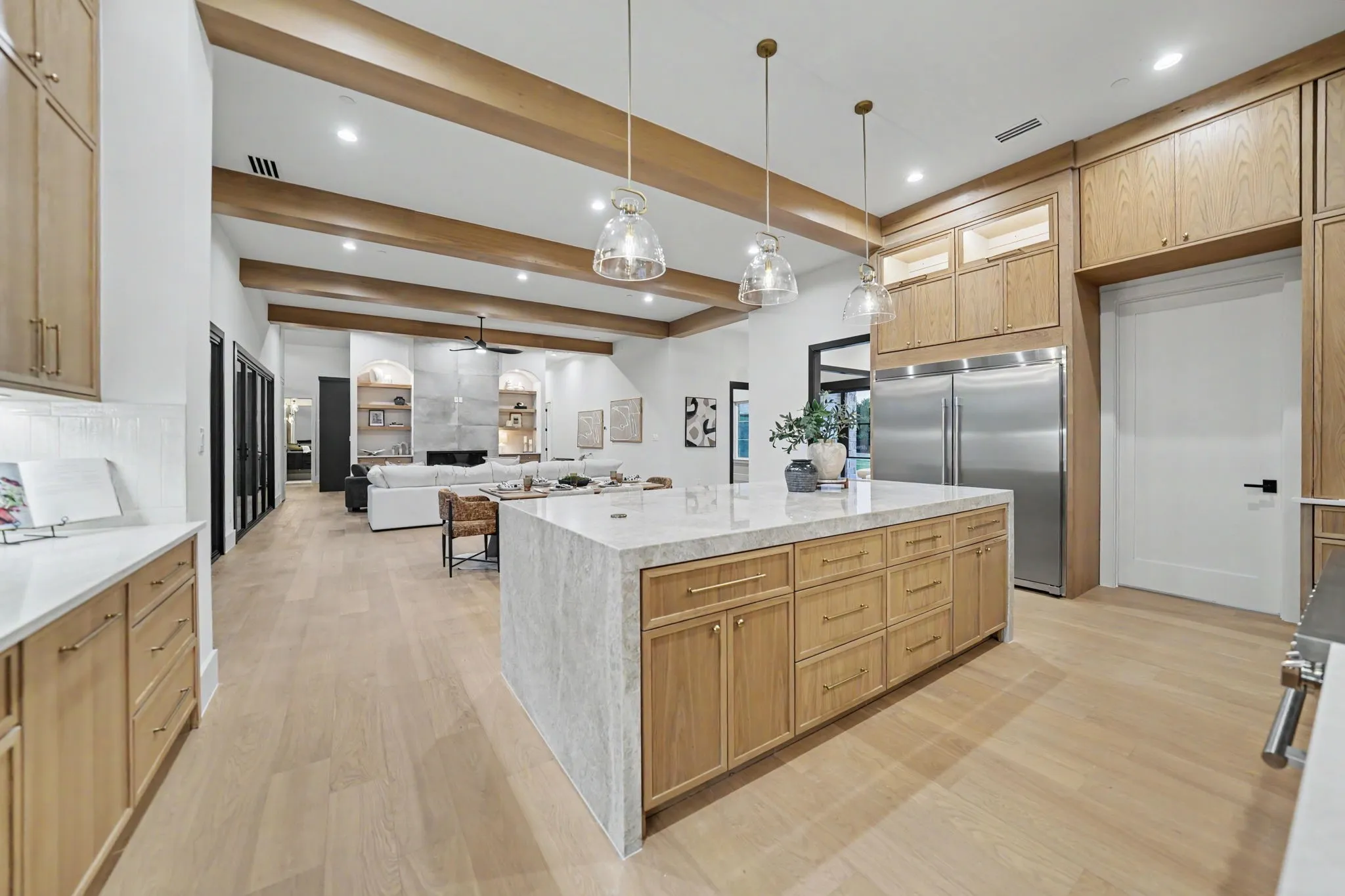 Gourmet kitchen with light wood-finish cabinetry, stainless steel refrigerator, and a large center island with a stone-finish countertop