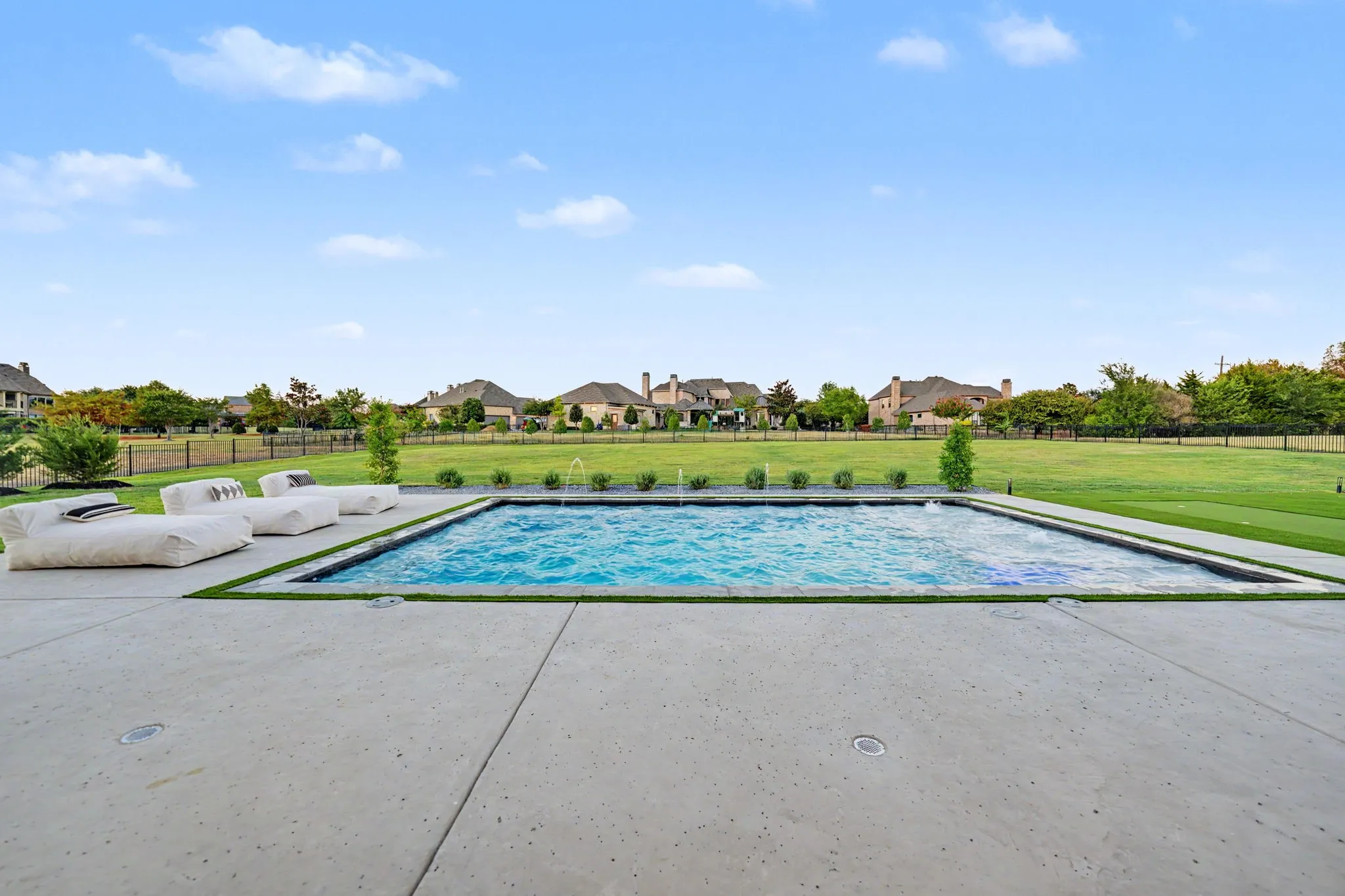 Rectangular swimming pool with integrated water features and surrounding artificial turf