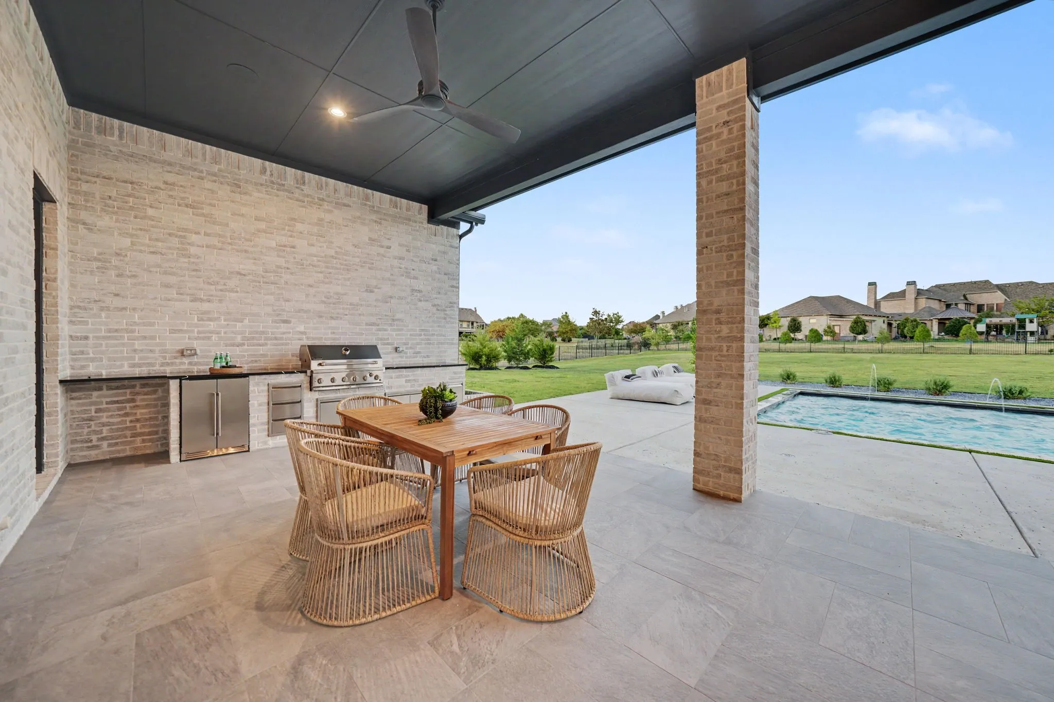 Expansive covered patio featuring a built-in outdoor kitchen with stainless steel appliances, a ceiling fan, and recessed lighting