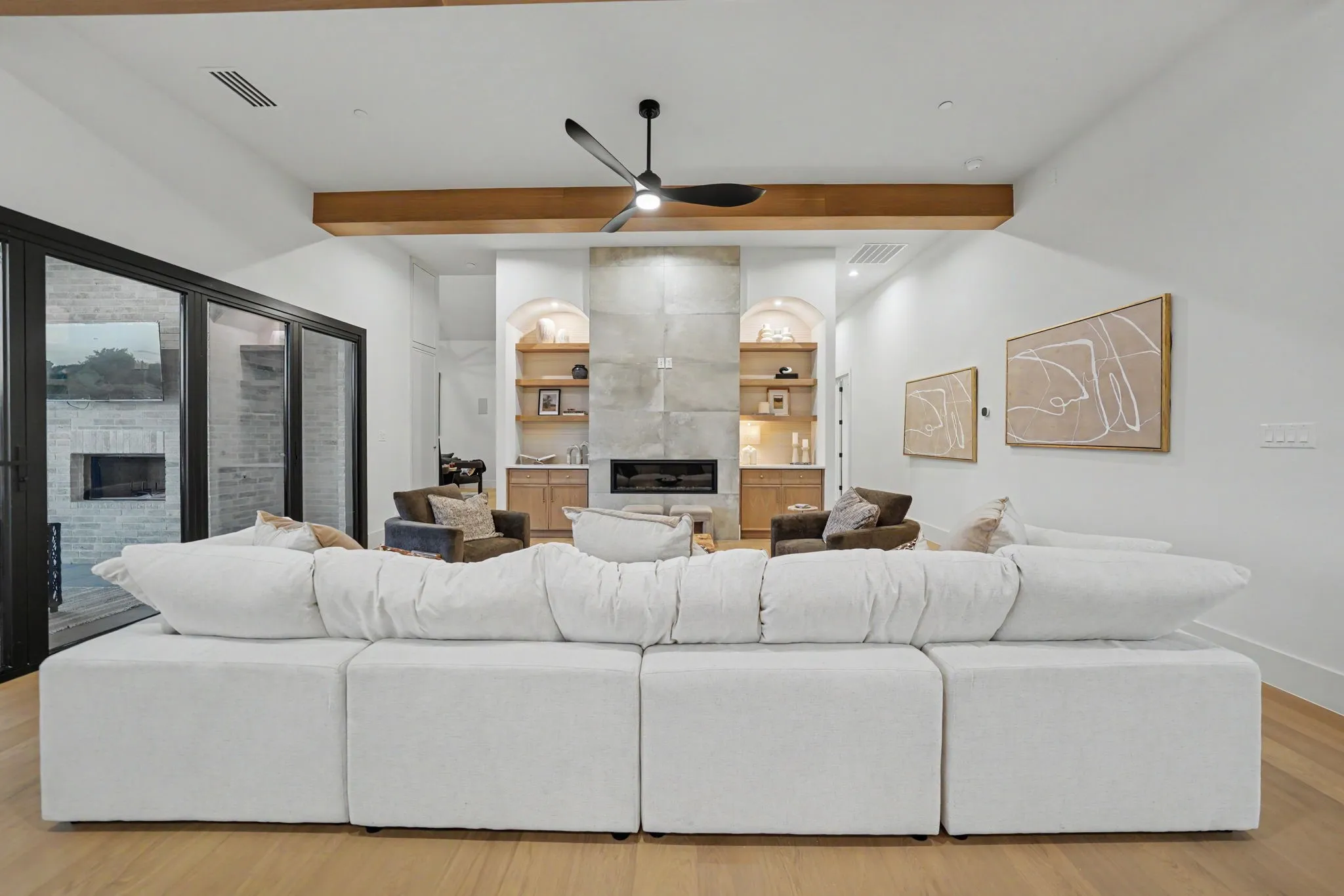 Living area featuring a stone-clad fireplace with hearth, wood-finish flooring, and exposed ceiling beams