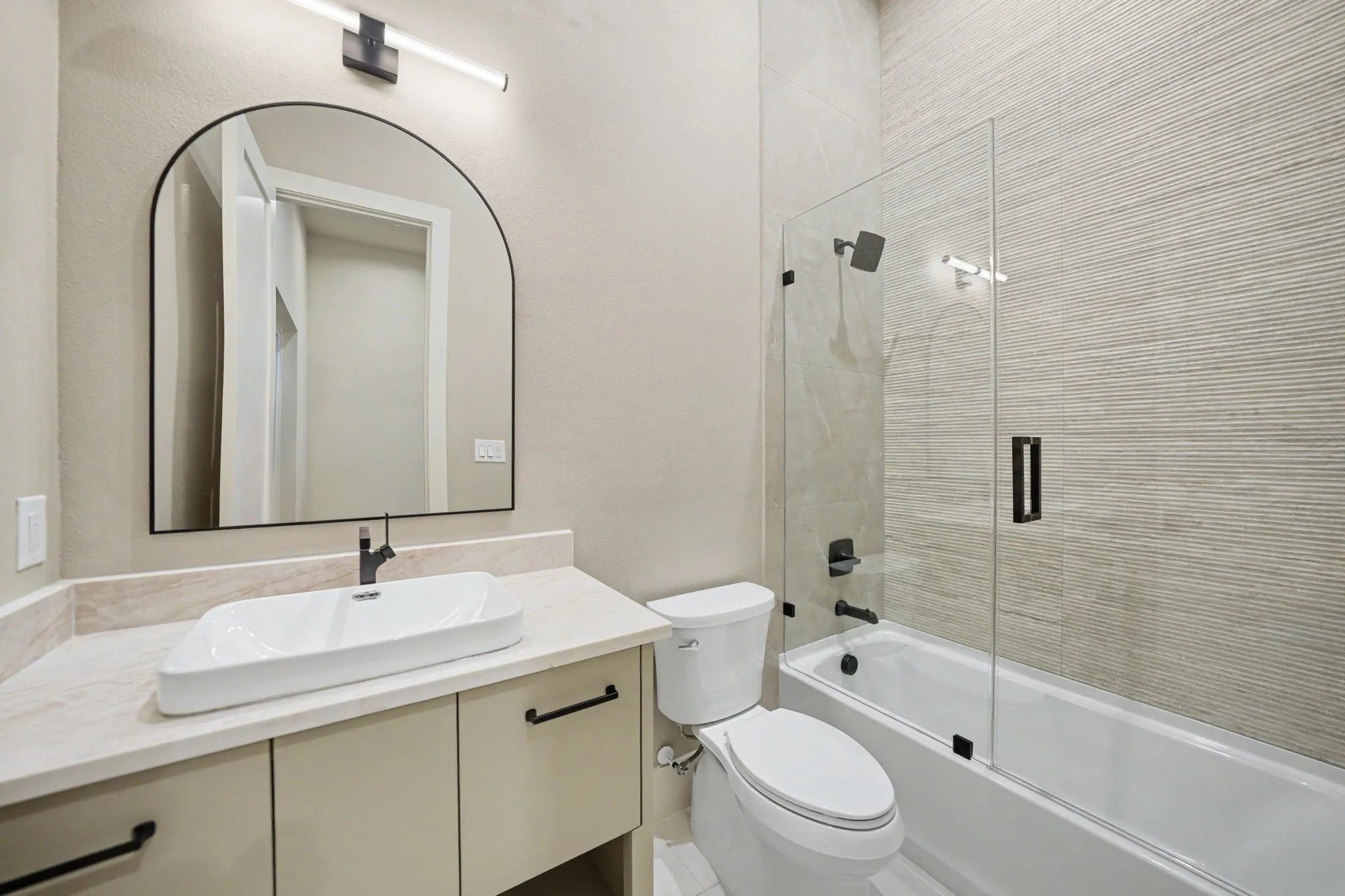 Vanity with a vessel sink, an arched mirror, and contemporary lighting