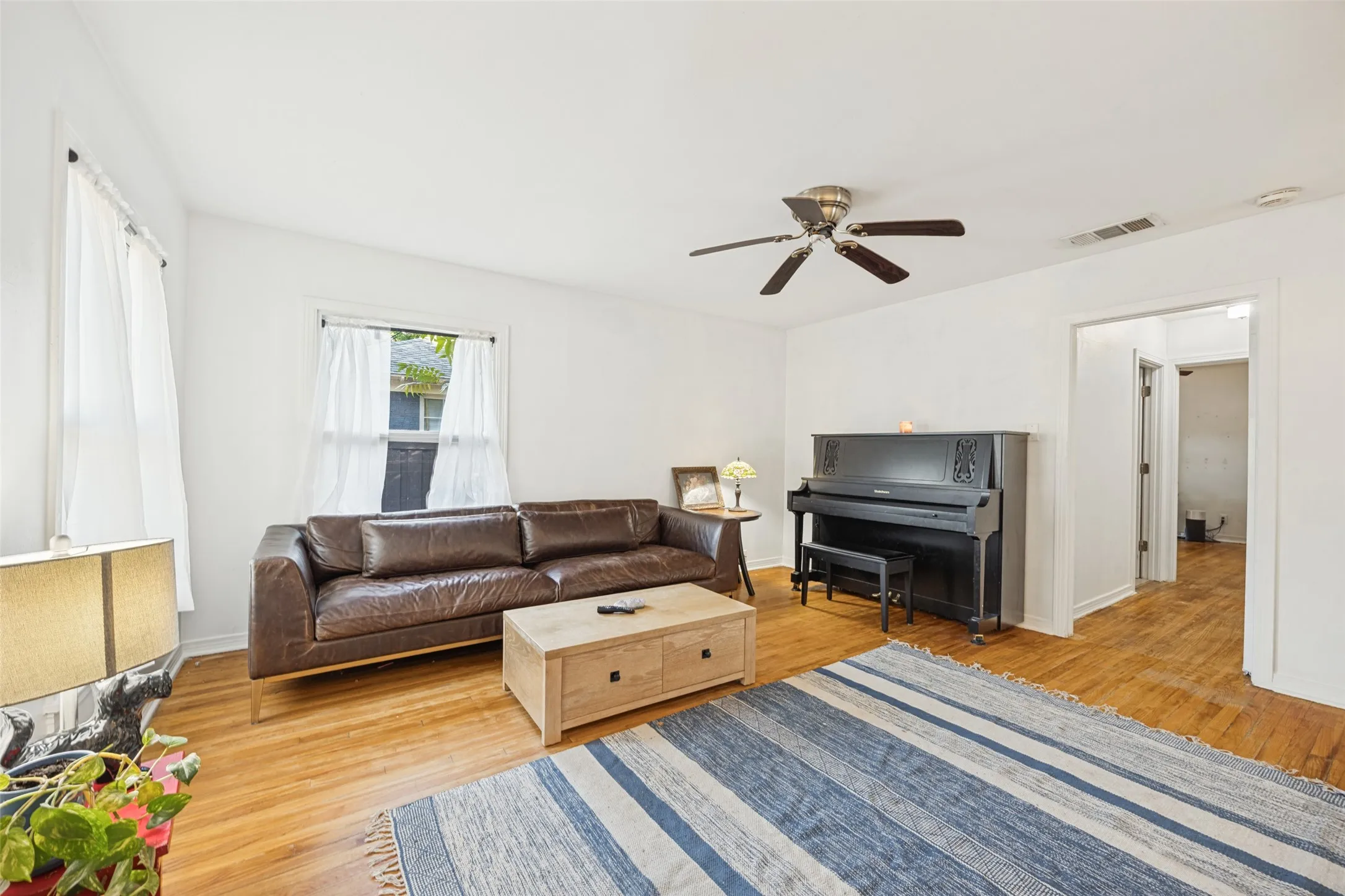 Hardwood flooring, freshly painted walls, ceiling fan, and window with natural light