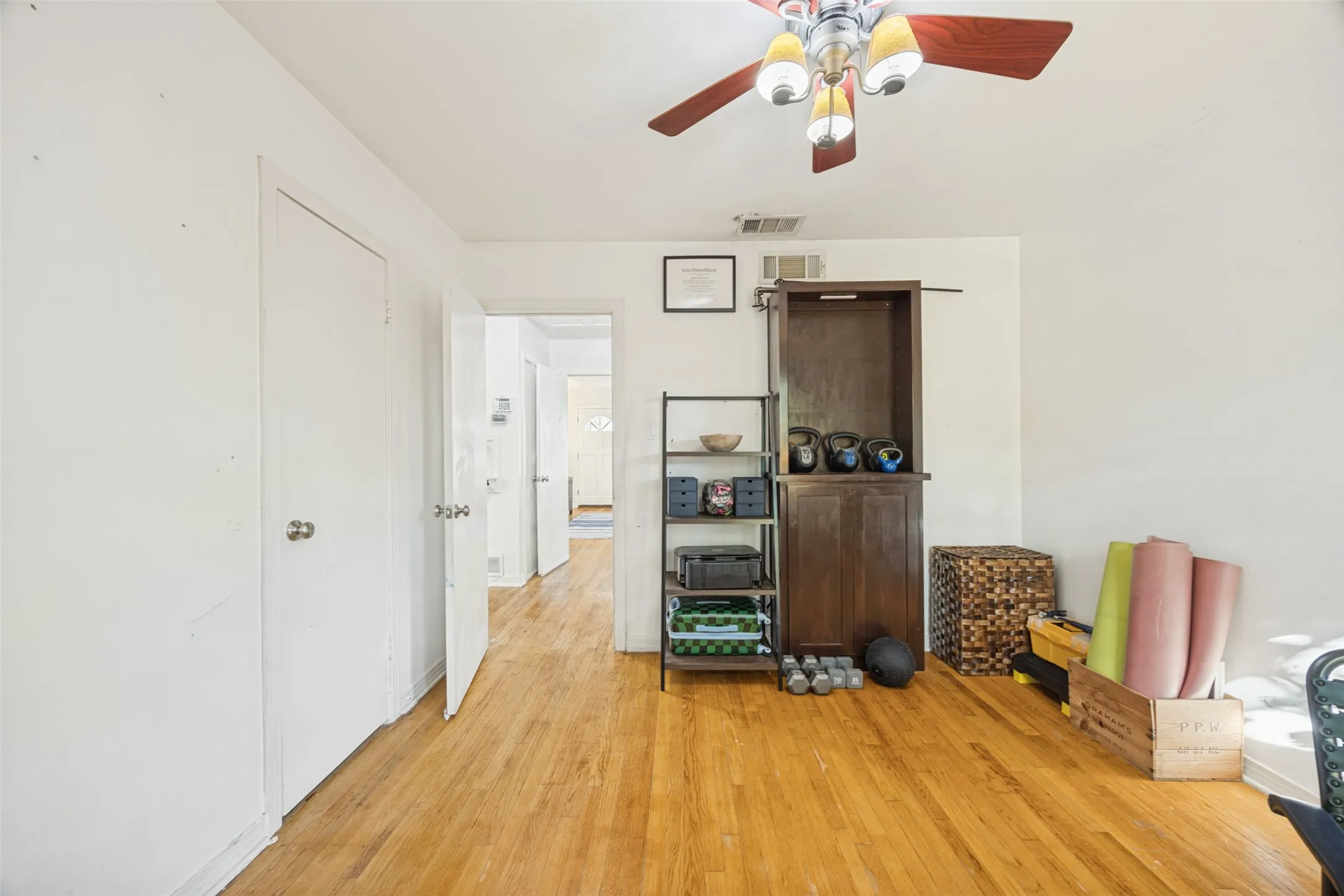 Hardwood flooring, white walls, and a ceiling fan with integrated lighting