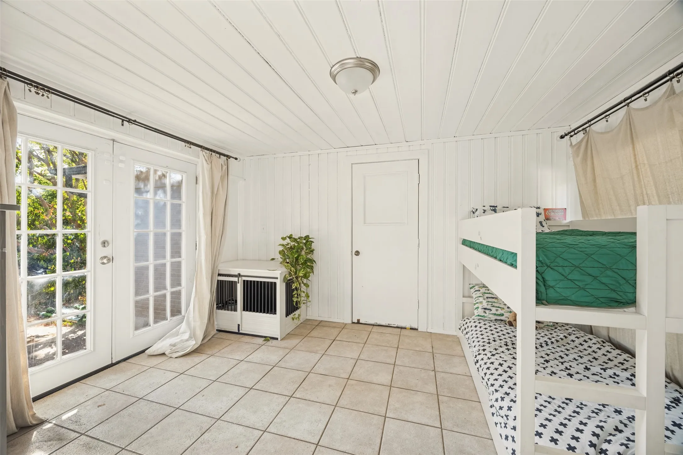 White paneled walls and ceiling, tile flooring, French doors with glass panes, and a flush-mount ceiling light fixture