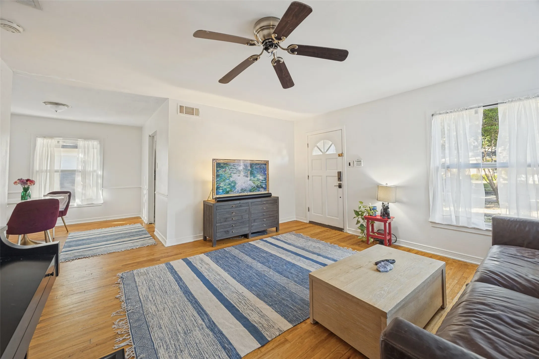 Hard wood flooring throughout, freshly painted white interior walls, and a ceiling fan with integrated lighting