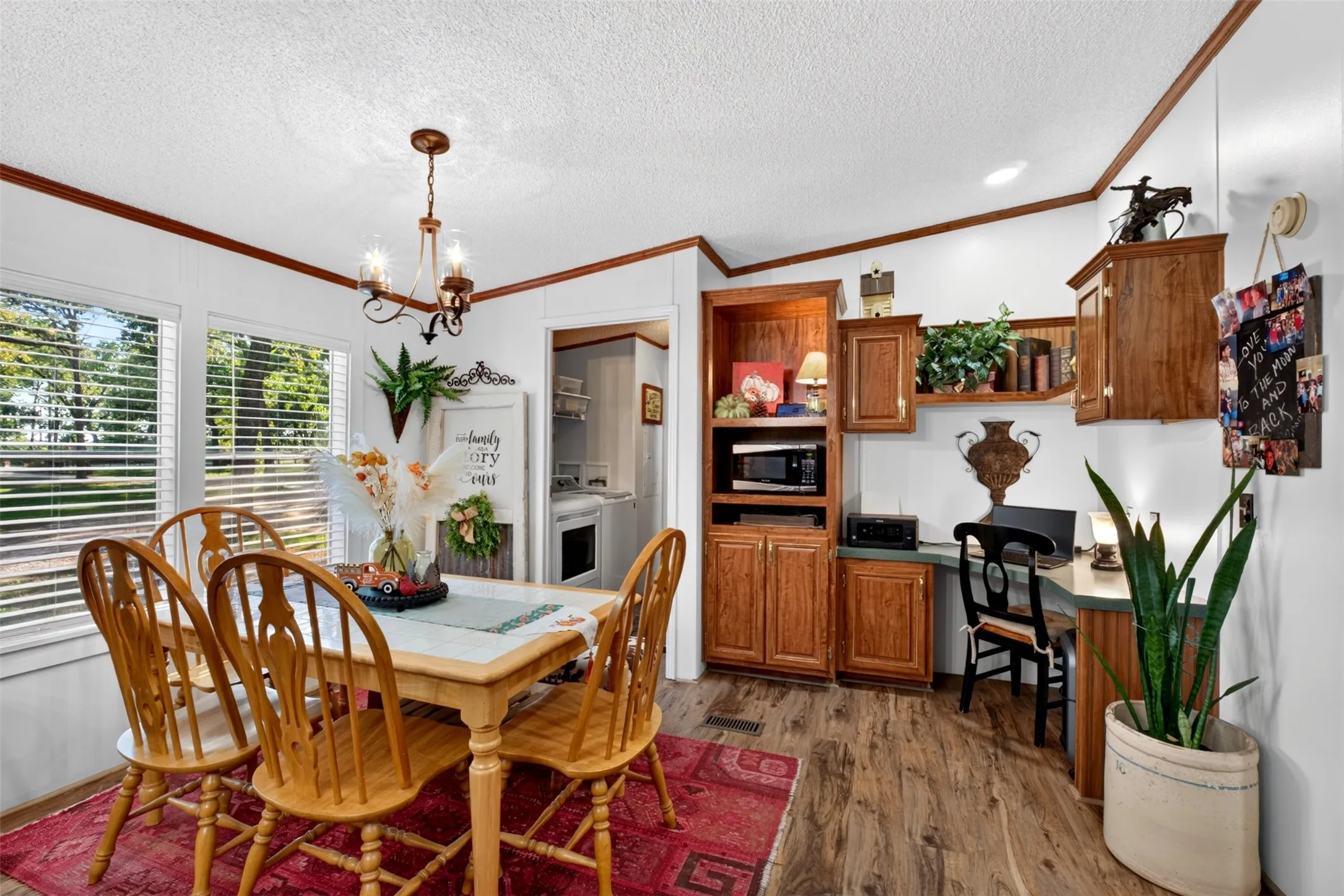 Dining room table with decorative fixture, natural light and home office in one corner and doorway to the laundry rom and walkin pantry.
