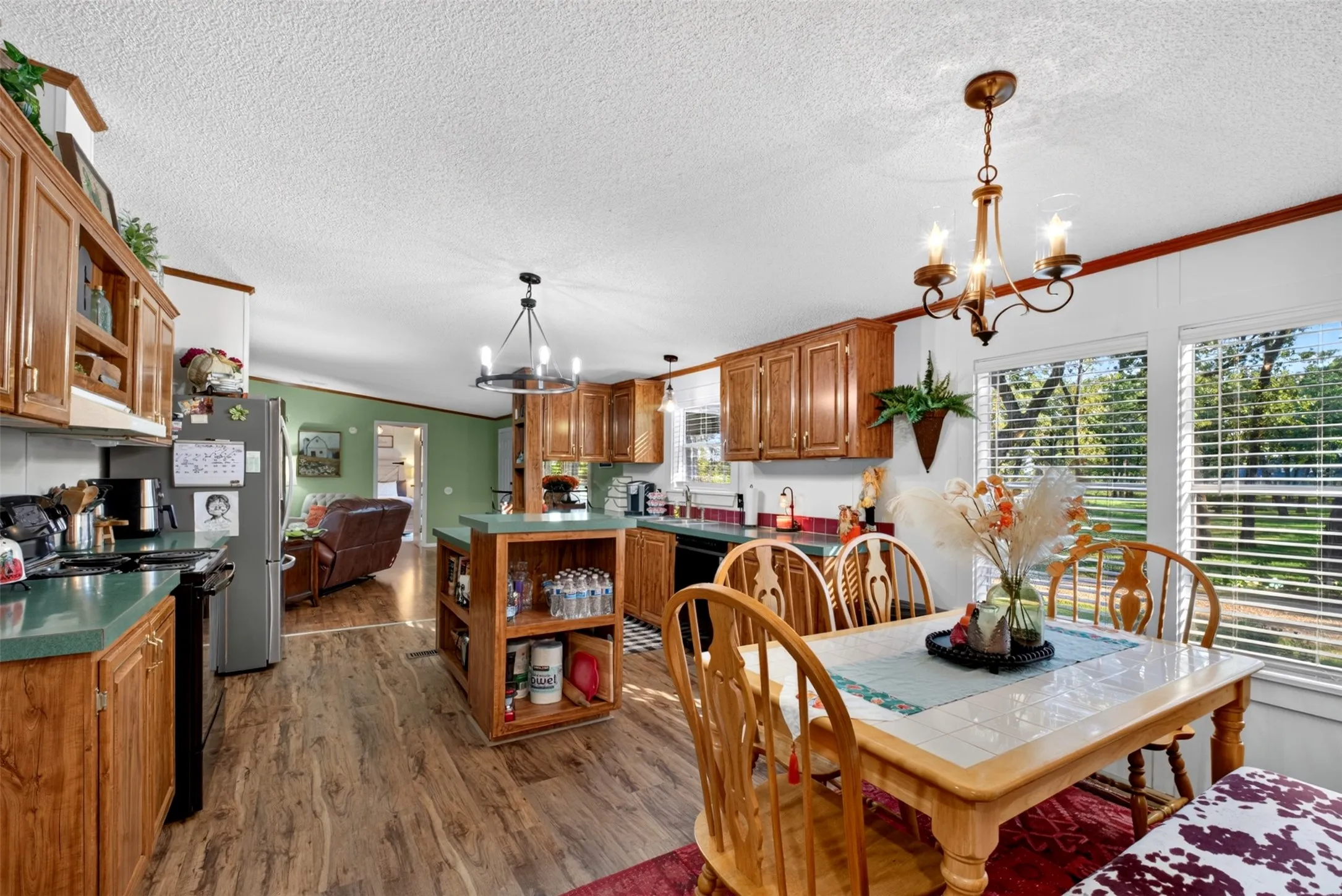 Wood-finish flooring throughout, kitchen featuring wood cabinetry, stainless steel refrigerator, and a kitchen island with built-in shelving