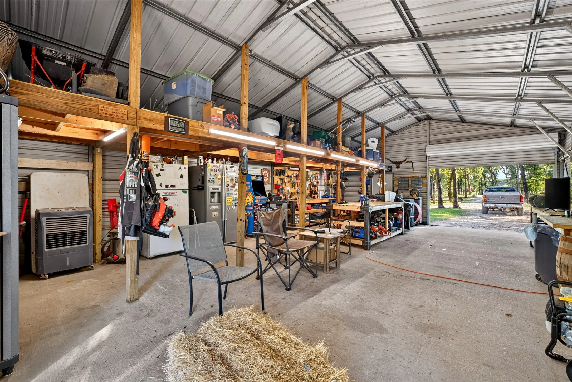Spacious metal-frame structure with a pitched roof, concrete flooring, and an integrated overhead storage loft